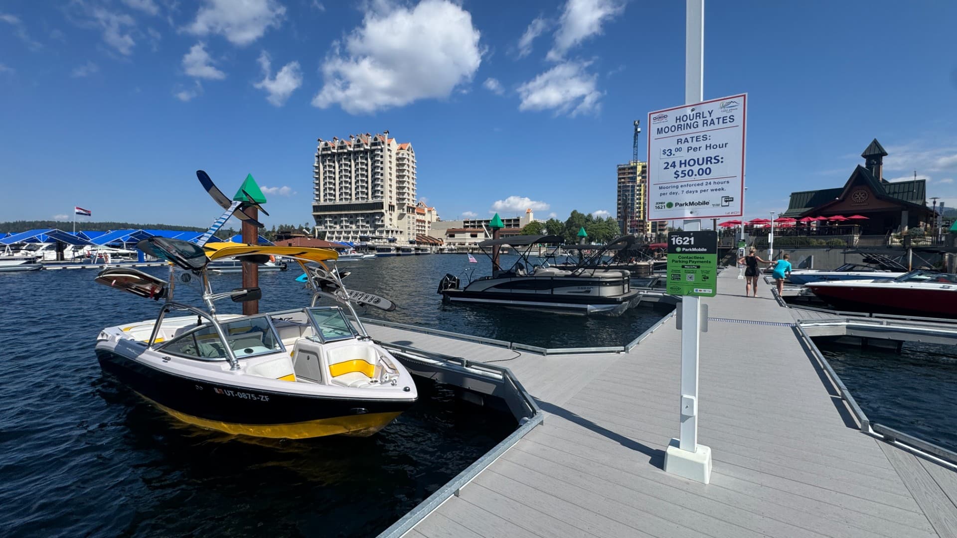 Pole-mounted informational signage at a marina displaying hourly mooring rates and payment instructions.