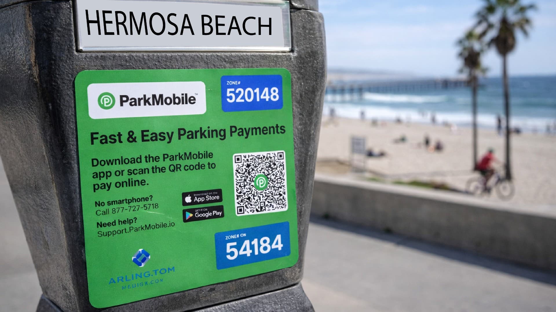 Close-up of a Hermosa Beach parking meter featuring a green ParkMobile payment sticker with QR code, set against a beach scene.