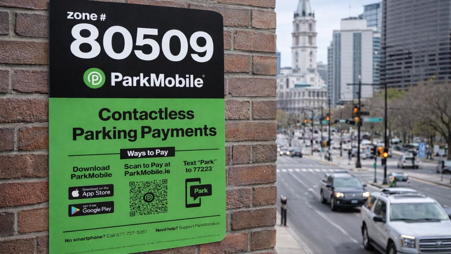 Close-up of a ParkMobile contactless parking sign mounted on a brick wall with a city street scene in the blurred background.