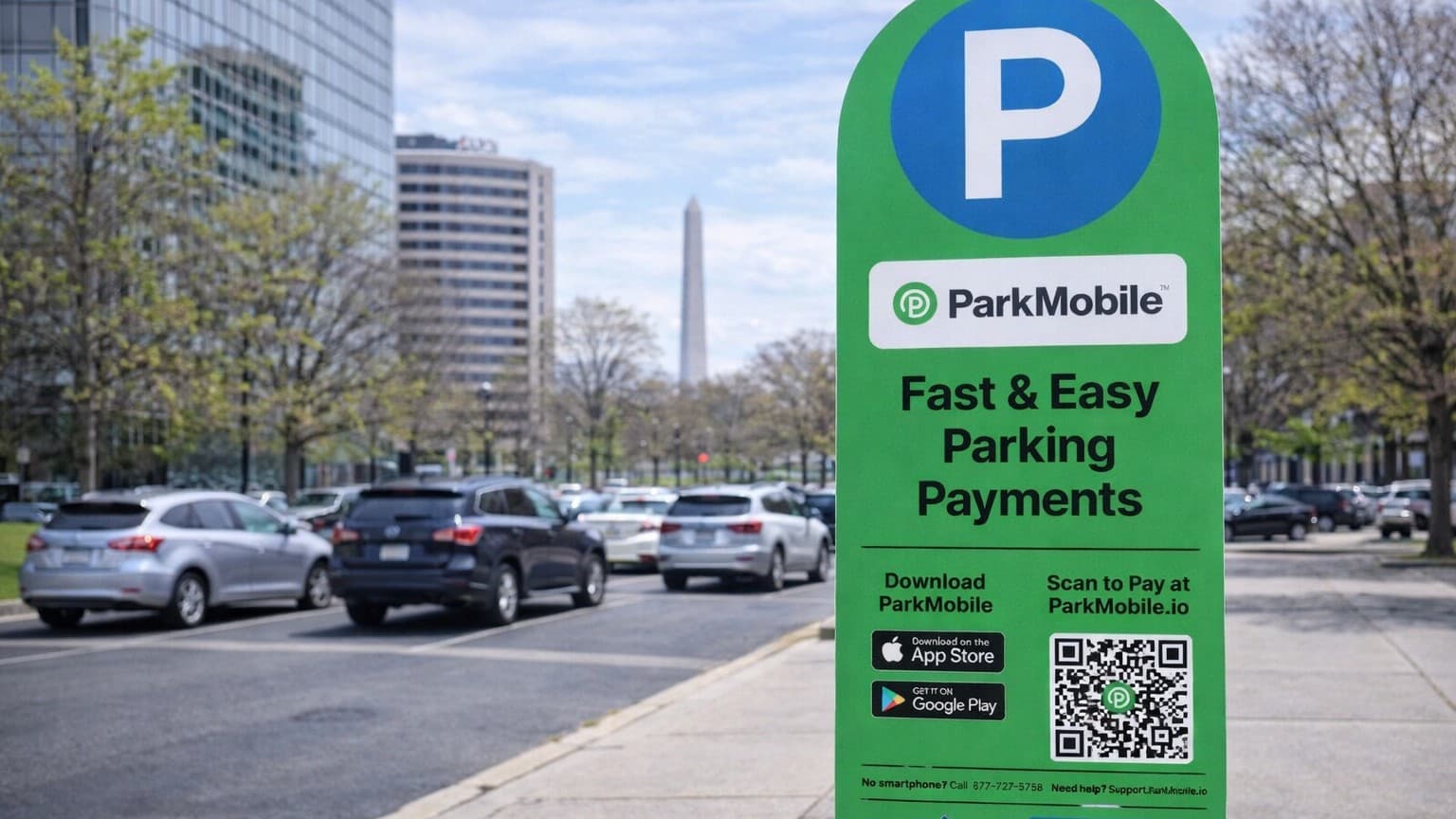 Green ParkMobile parking sign with a QR code and app store logos, standing near a street with parked cars and the Washington Monument.