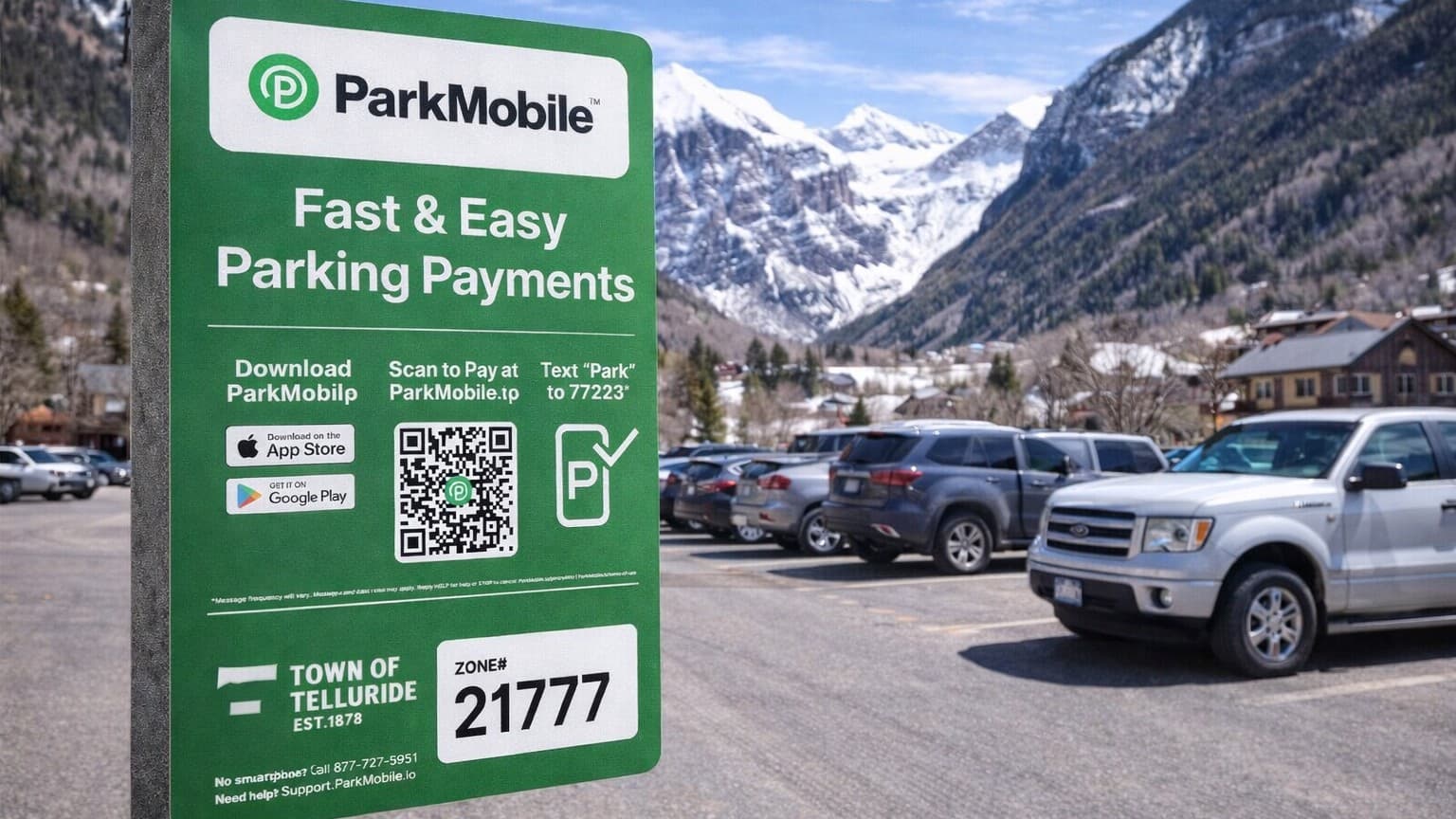 Green ParkMobile parking sign with QR code and instructions, located in a lot with snow-capped mountains in the background.