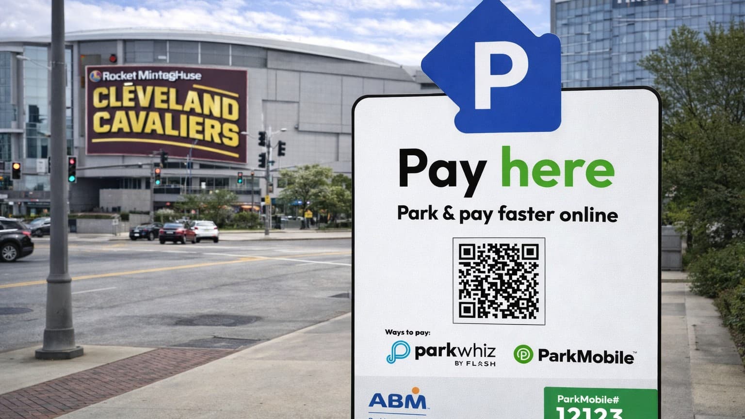 Close-up of a 'Pay Here' parking sign with a QR code, set against the backdrop of the Rocket Mortgage FieldHouse arena.