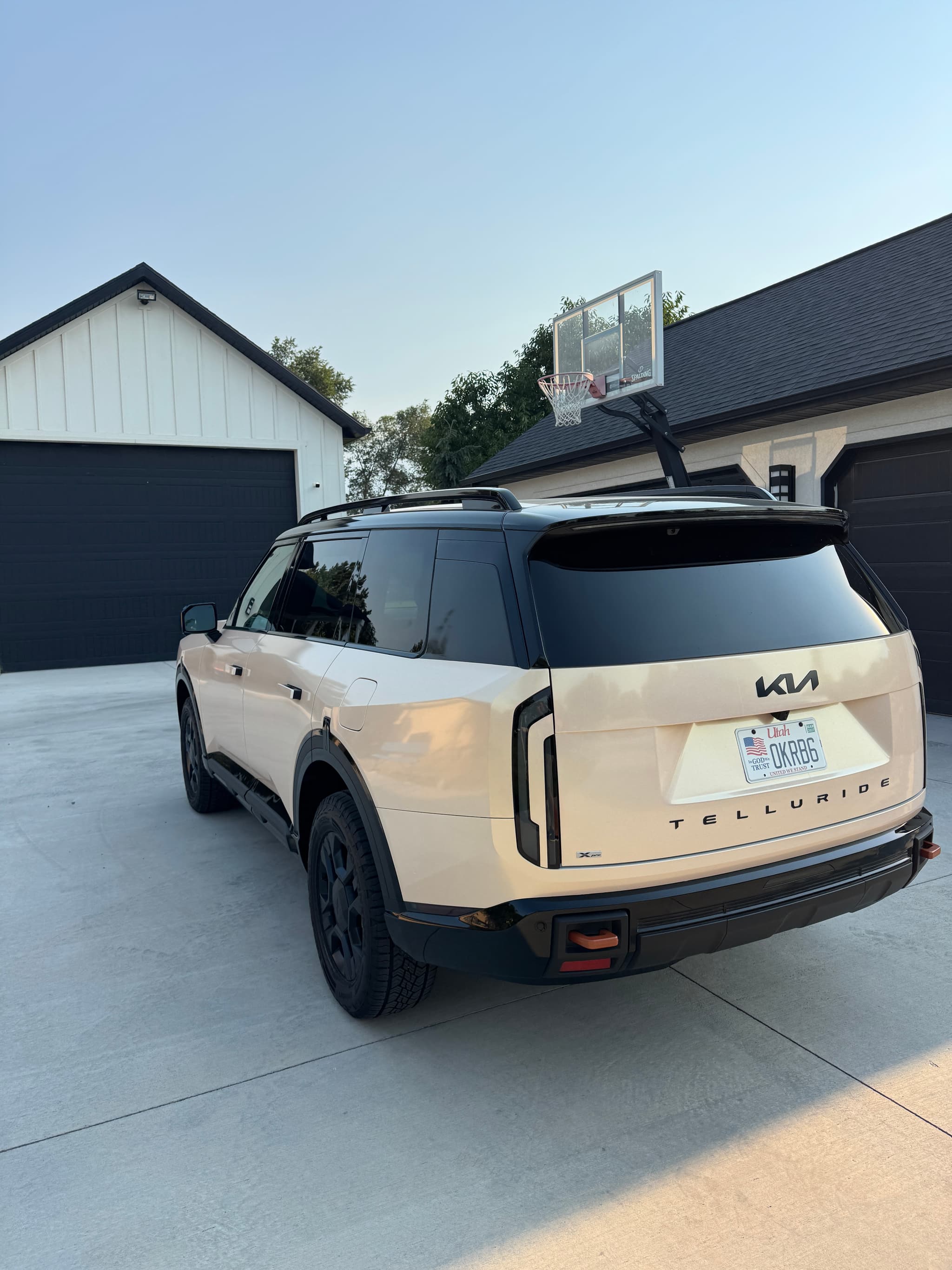Rear view of a two-tone beige and black Kia Telluride SUV wrapped in custom vinyl parked on a driveway.