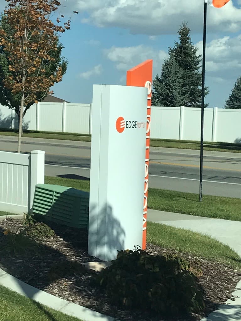 Outdoor monument sign for Edge Homes with white and orange panels.