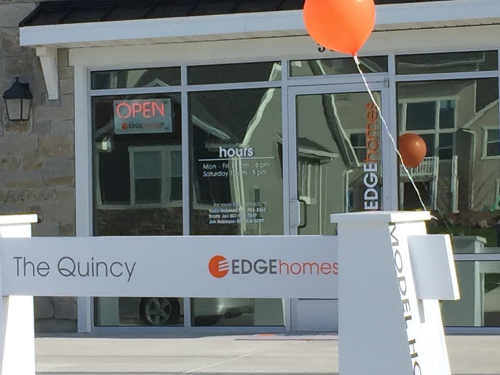 Exterior of an Edge Homes model home named The Quincy with an open sign and orange balloons.