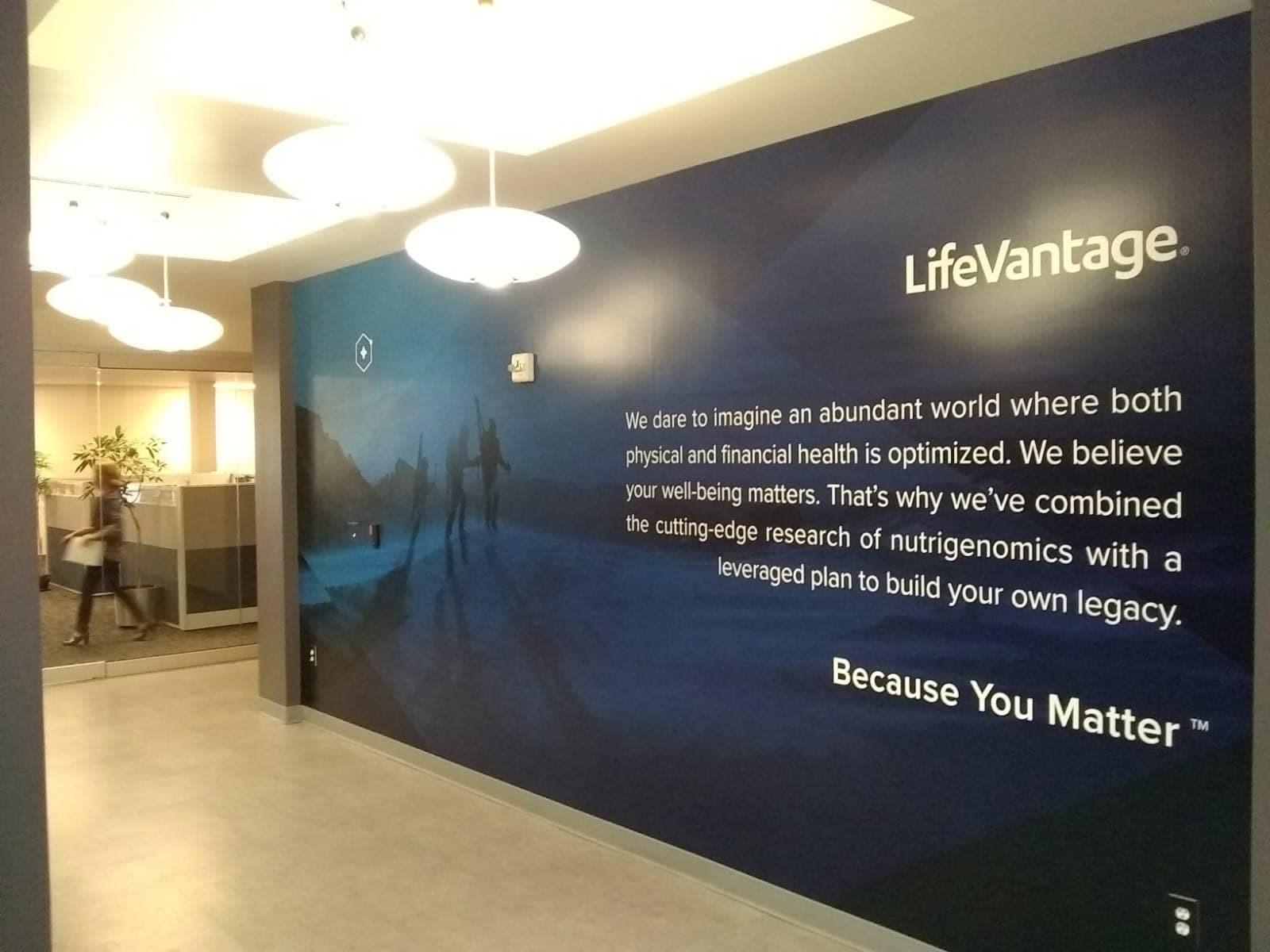 Branded LifeVantage wall graphic featuring corporate mission statement in a modern office hallway.