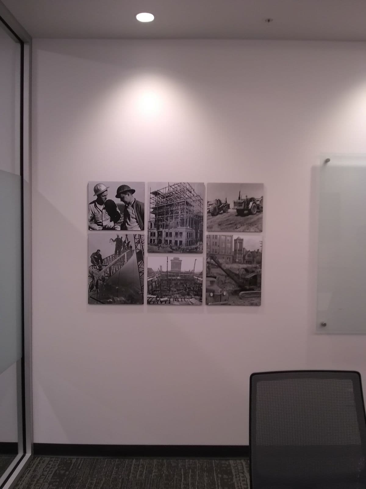 Six black-and-white historical construction photos arranged in a grid display on an office wall.