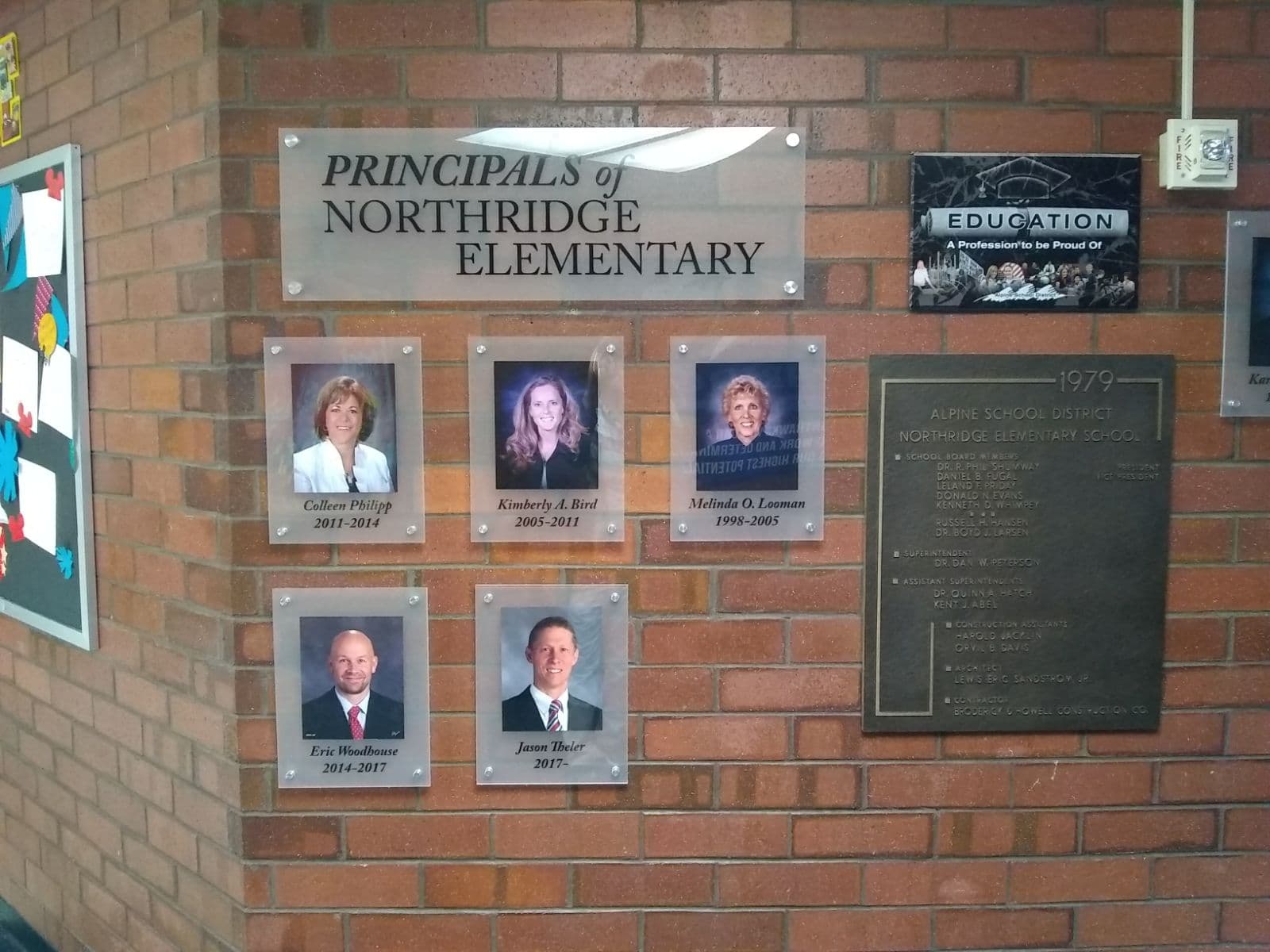 Acrylic wall plaques displaying portraits of Northridge Elementary principals mounted on a brick wall.