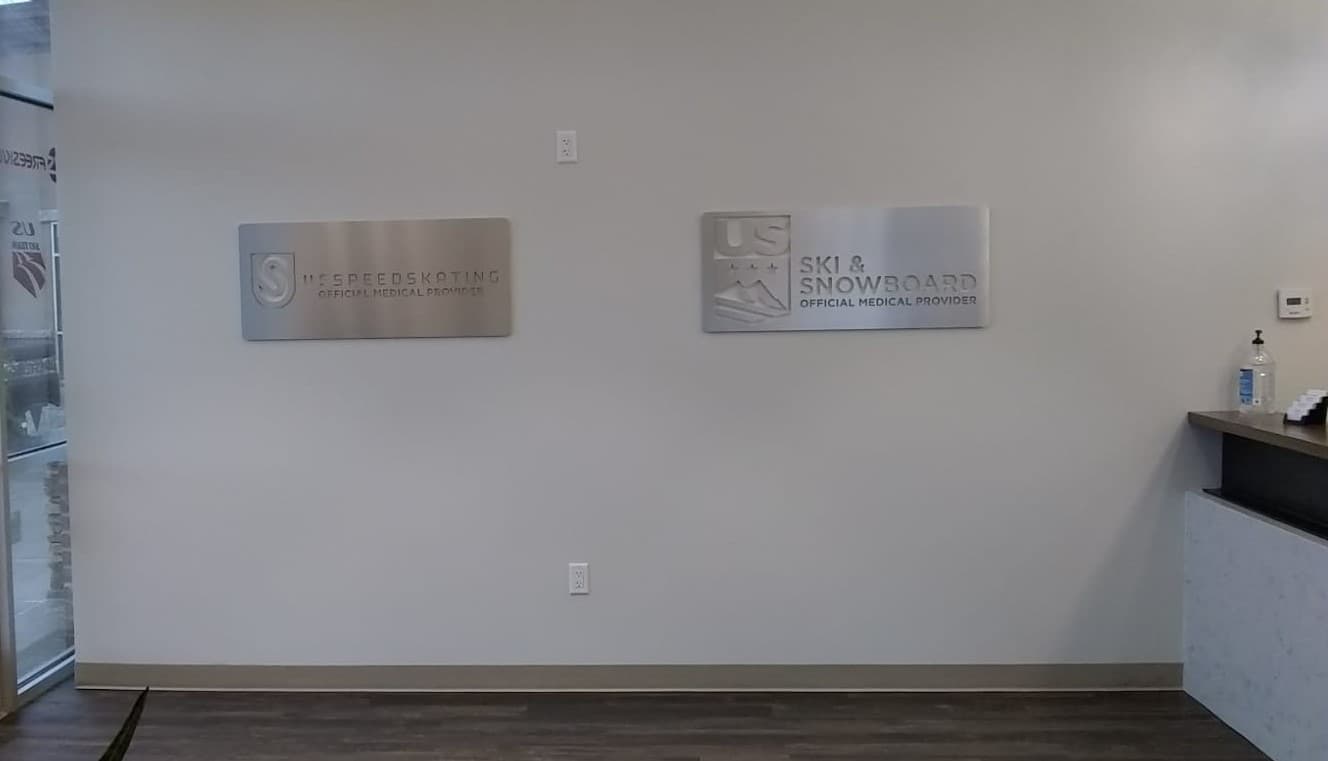 Brushed metal lobby signs reading US Speedskating and US Ski & Snowboard Official Medical Provider.