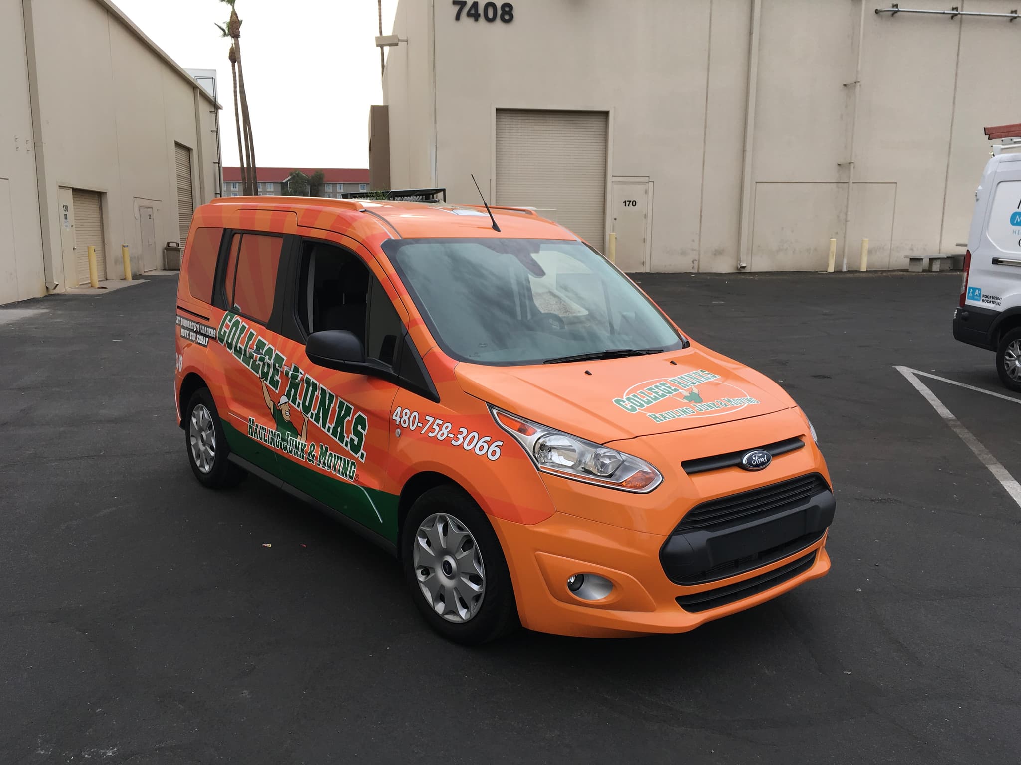 Orange and green branded Ford Transit van for College Hunks Hauling Junk parked in a lot.