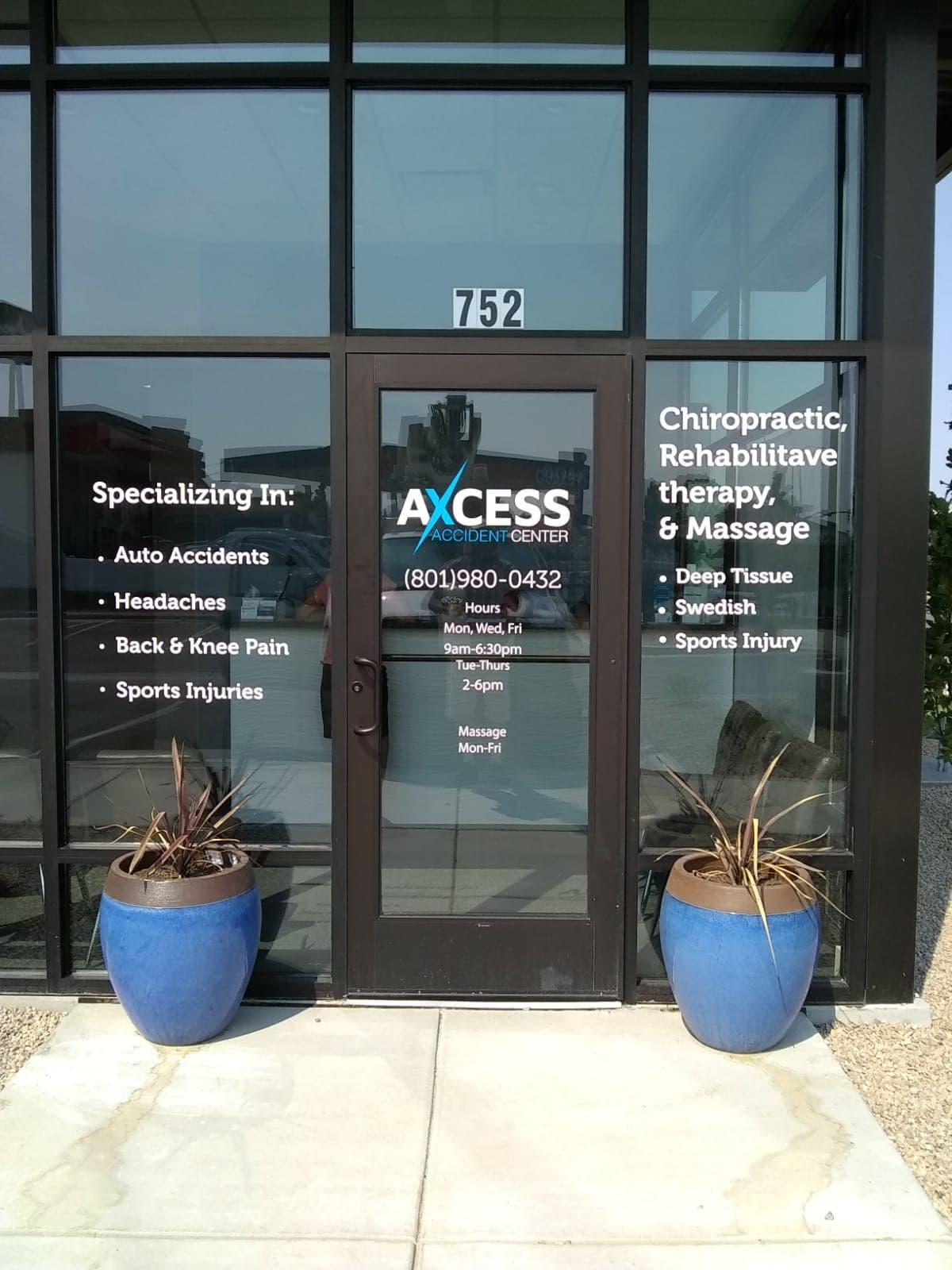 Storefront glass door and windows displaying white vinyl decals for Axcess Accident Center.