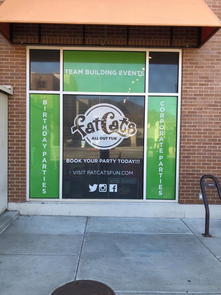 Fat Cats storefront window graphics displaying birthday parties, corporate parties, and team building events.