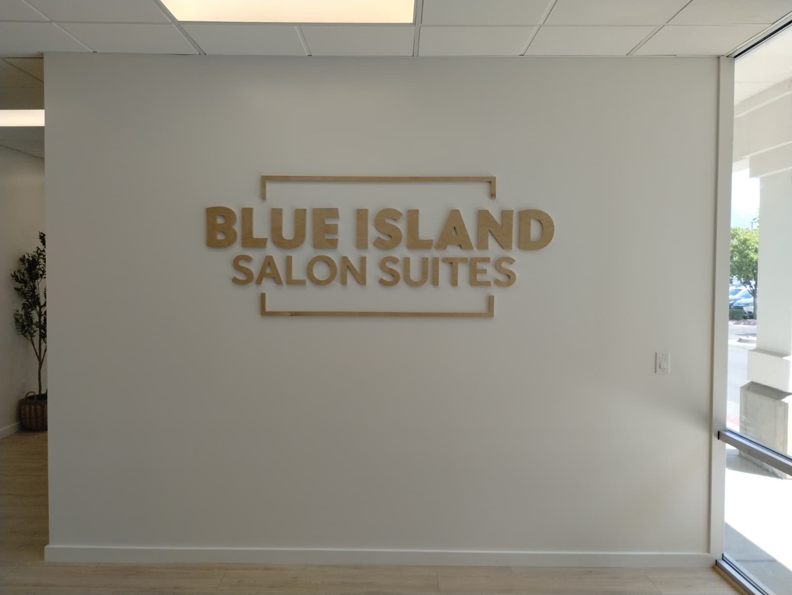 Gold dimensional wall sign reading Blue Island Salon Suites mounted in a modern lobby.