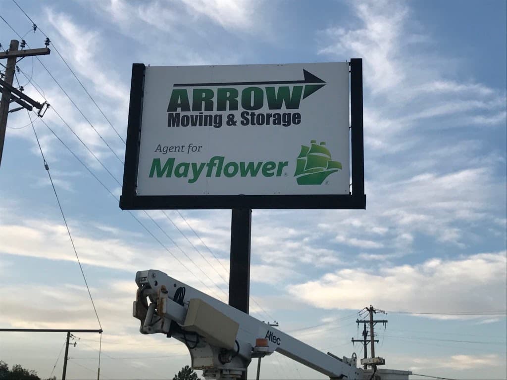 Outdoor elevated sign for Arrow Moving & Storage, an agent for Mayflower, against a cloudy sky.