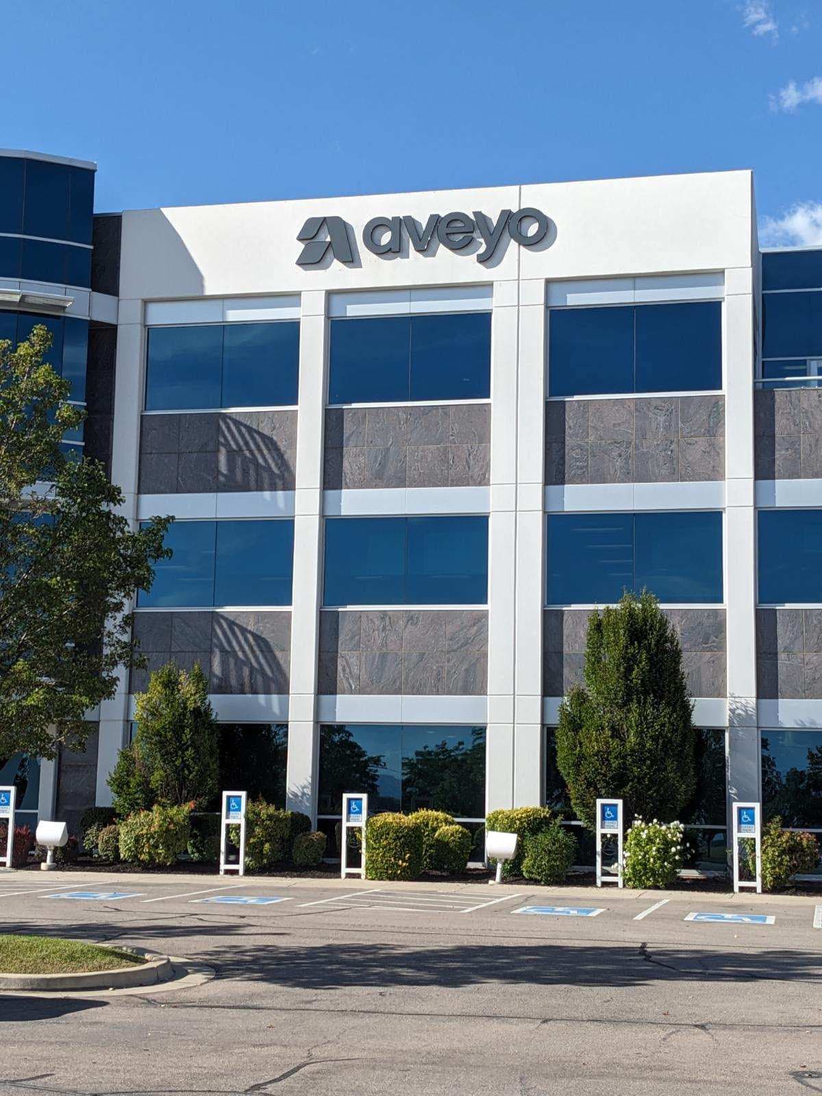 Exterior view of a multi-story commercial office building featuring an Aveyo logo sign at the top roofline.