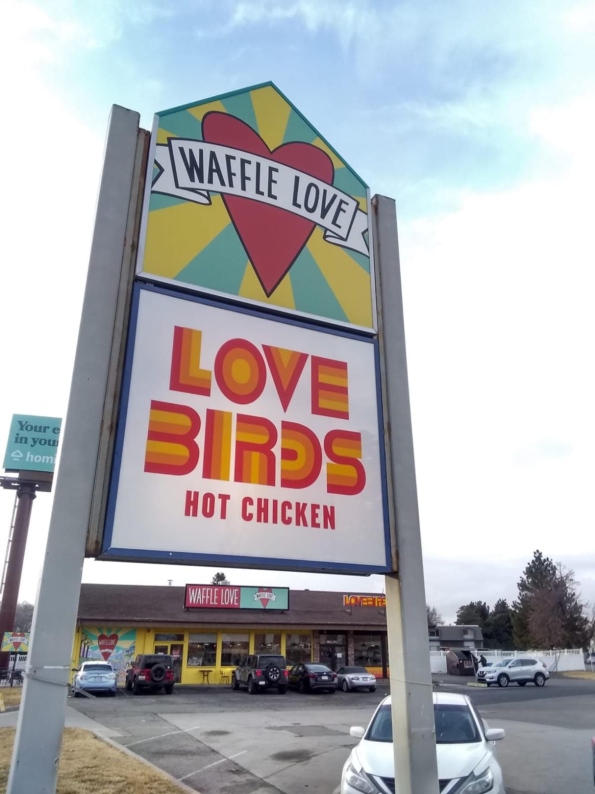 Outdoor pylon sign for Waffle Love and Lovebirds Hot Chicken in front of the restaurant storefront.