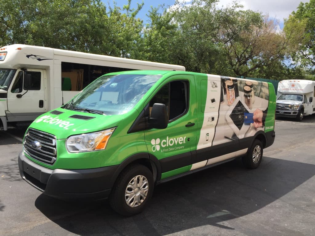 Green Ford Transit van wrapped with Clover A First Data Company graphics parked outdoors.