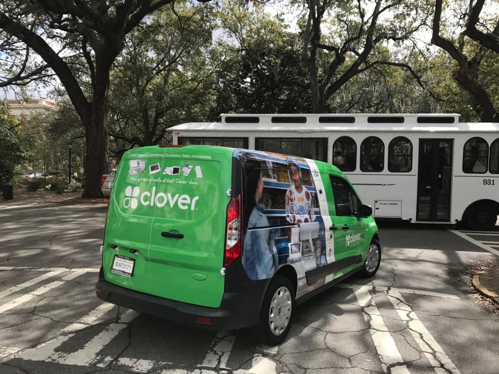 Green Clover branded van featuring a custom full vehicle wrap driving on a city street.