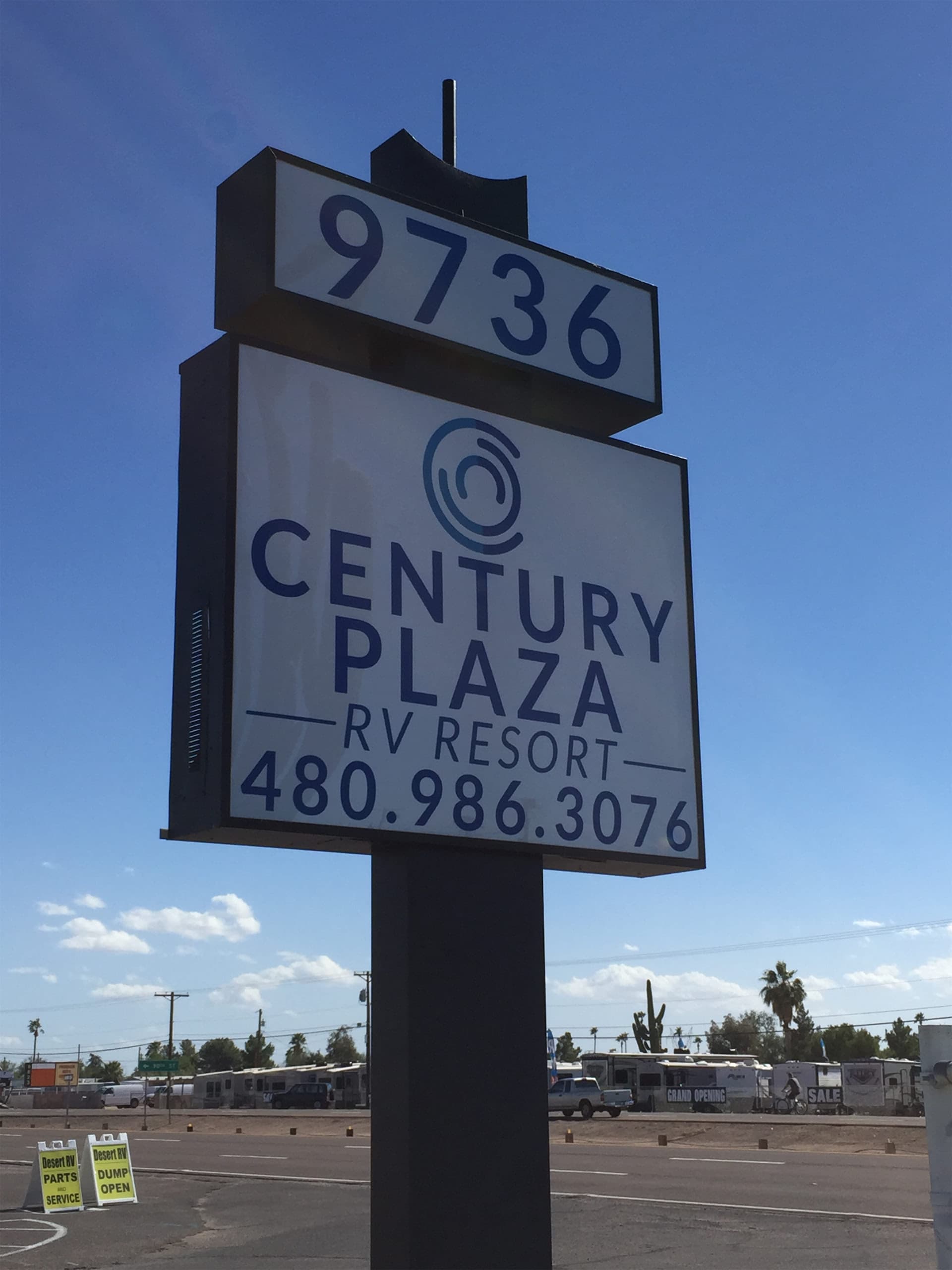 A tall white and blue pylon sign for Century Plaza RV Resort set against a clear blue sky.