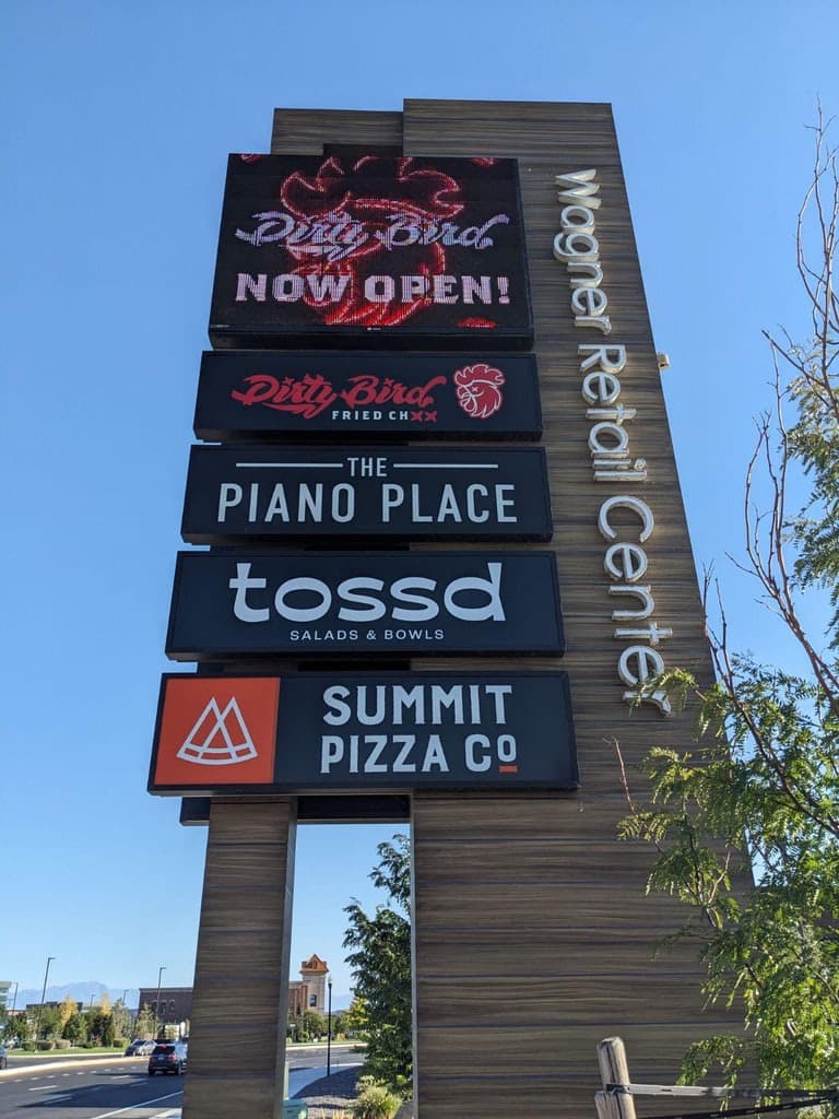 Tall Wagner Retail Center pylon sign with digital LED display and tenant panels including Tossd and Summit Pizza Co.