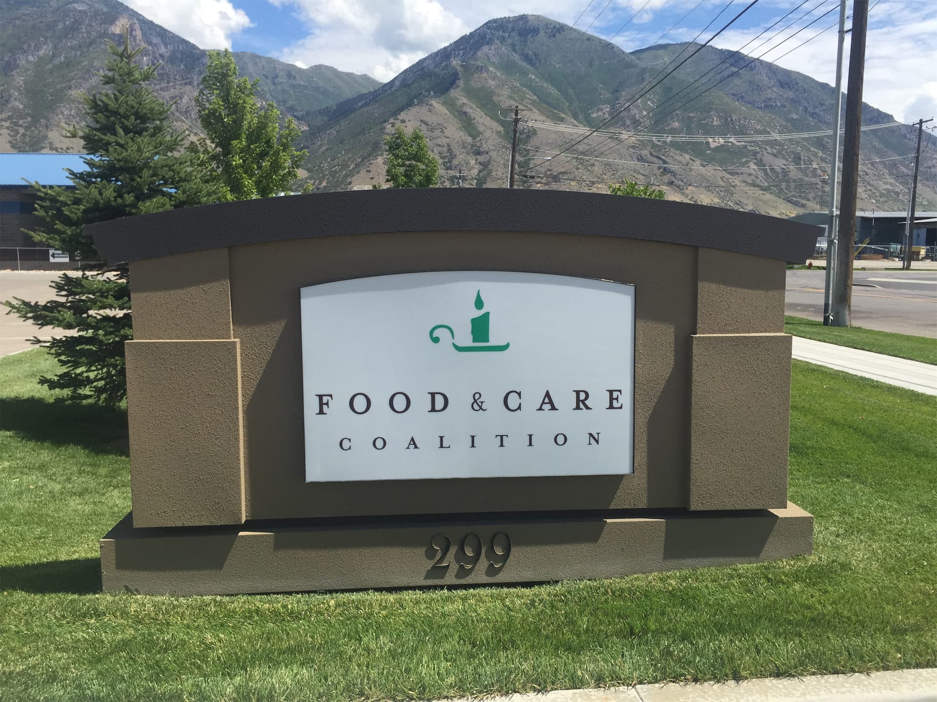 Outdoor monument sign for Food & Care Coalition with mountains in the background.
