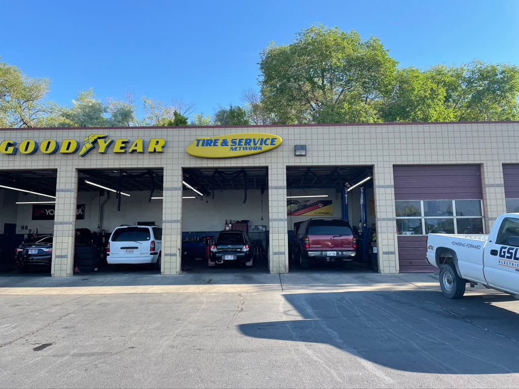 Exterior view of a Goodyear Tire & Service Network shop featuring yellow building signs and open service bays.