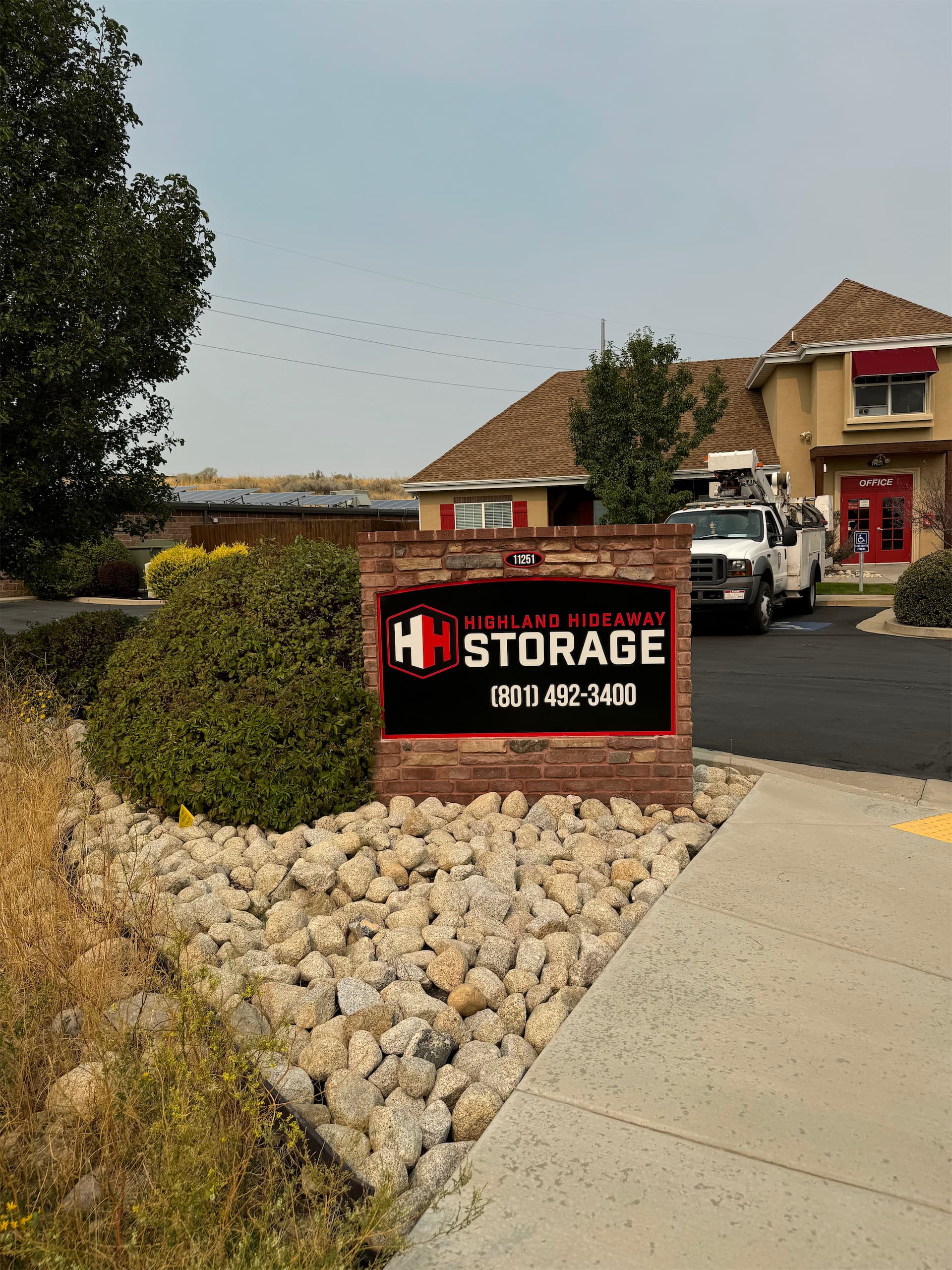 Brick monument sign for Highland Hideaway Storage with red and white logo.