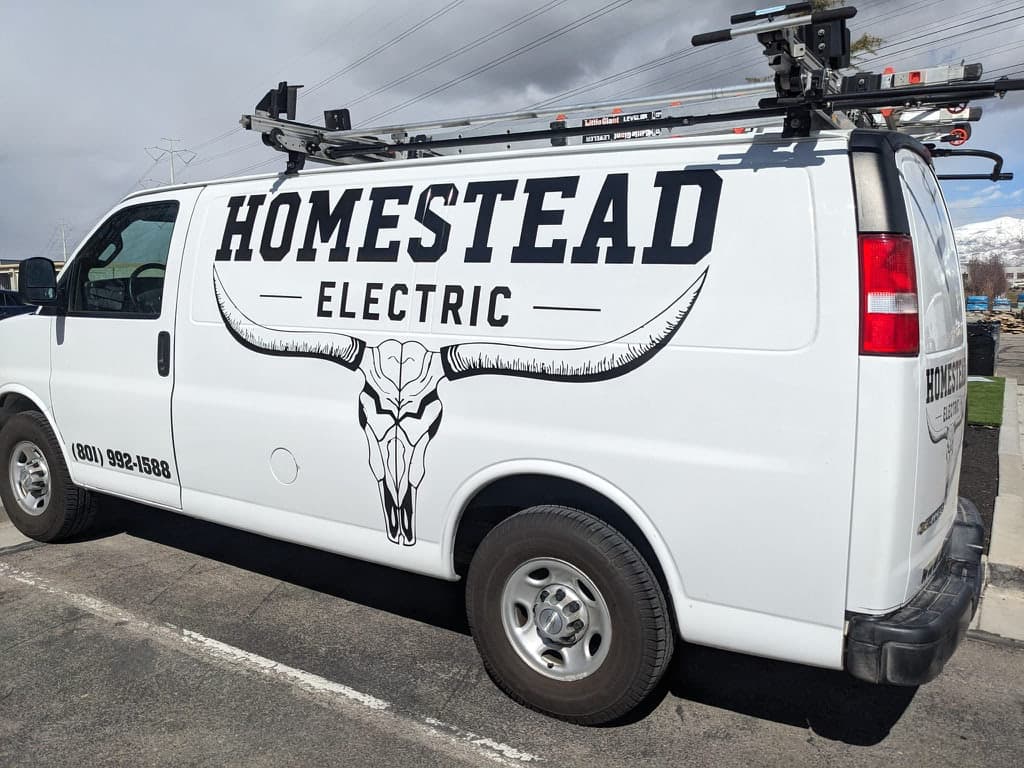 White Homestead Electric work van featuring custom black vehicle graphics and a longhorn skull logo.