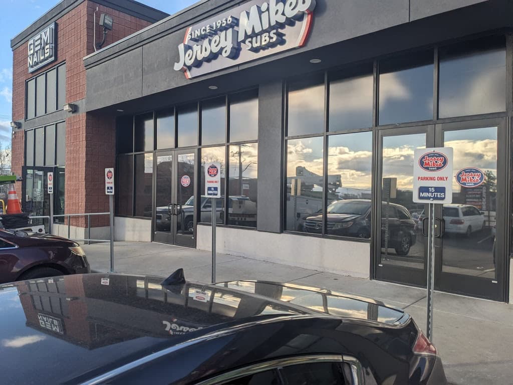 Exterior view of a Jersey Mike's Subs storefront featuring channel letter building signage and reserved parking signs.
