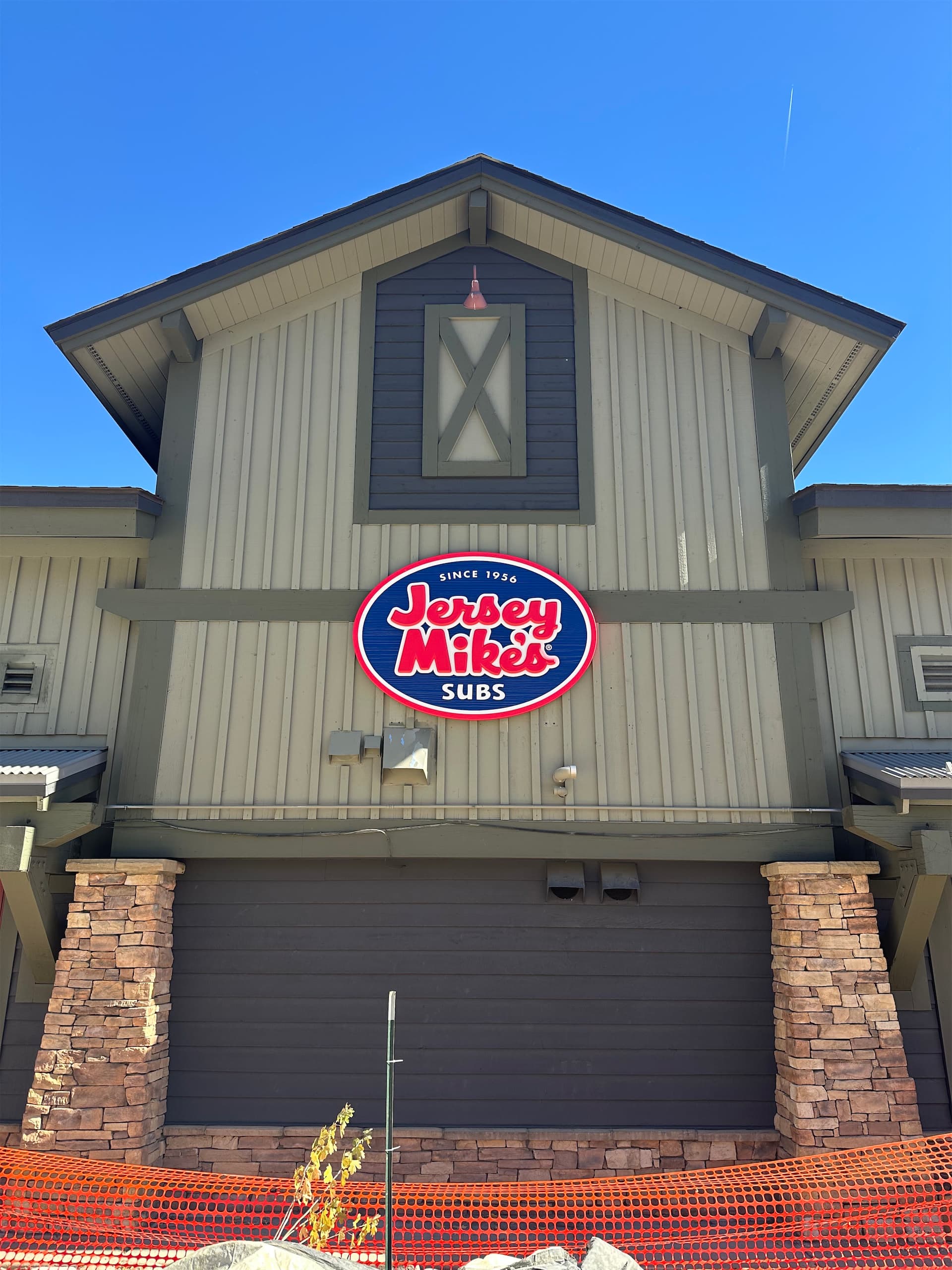 Illuminated Jersey Mike's Subs oval logo sign mounted on the exterior wall of a building.