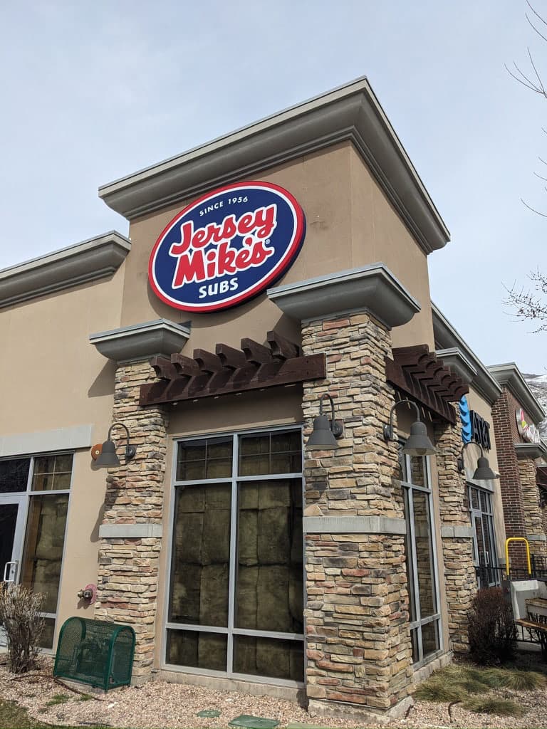 Jersey Mike's Subs exterior building sign mounted on a beige wall with stone accents.