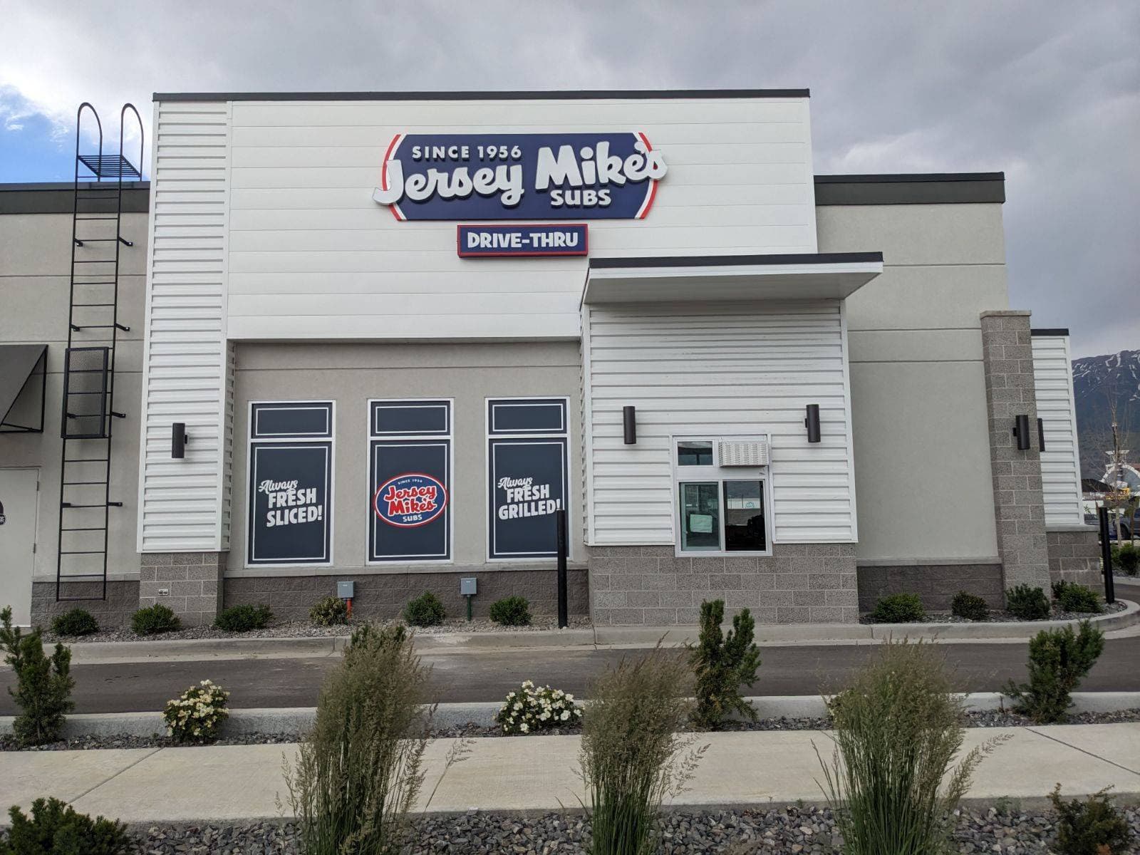 Jersey Mike's Subs drive-thru exterior featuring illuminated channel letter building signage and window decals.