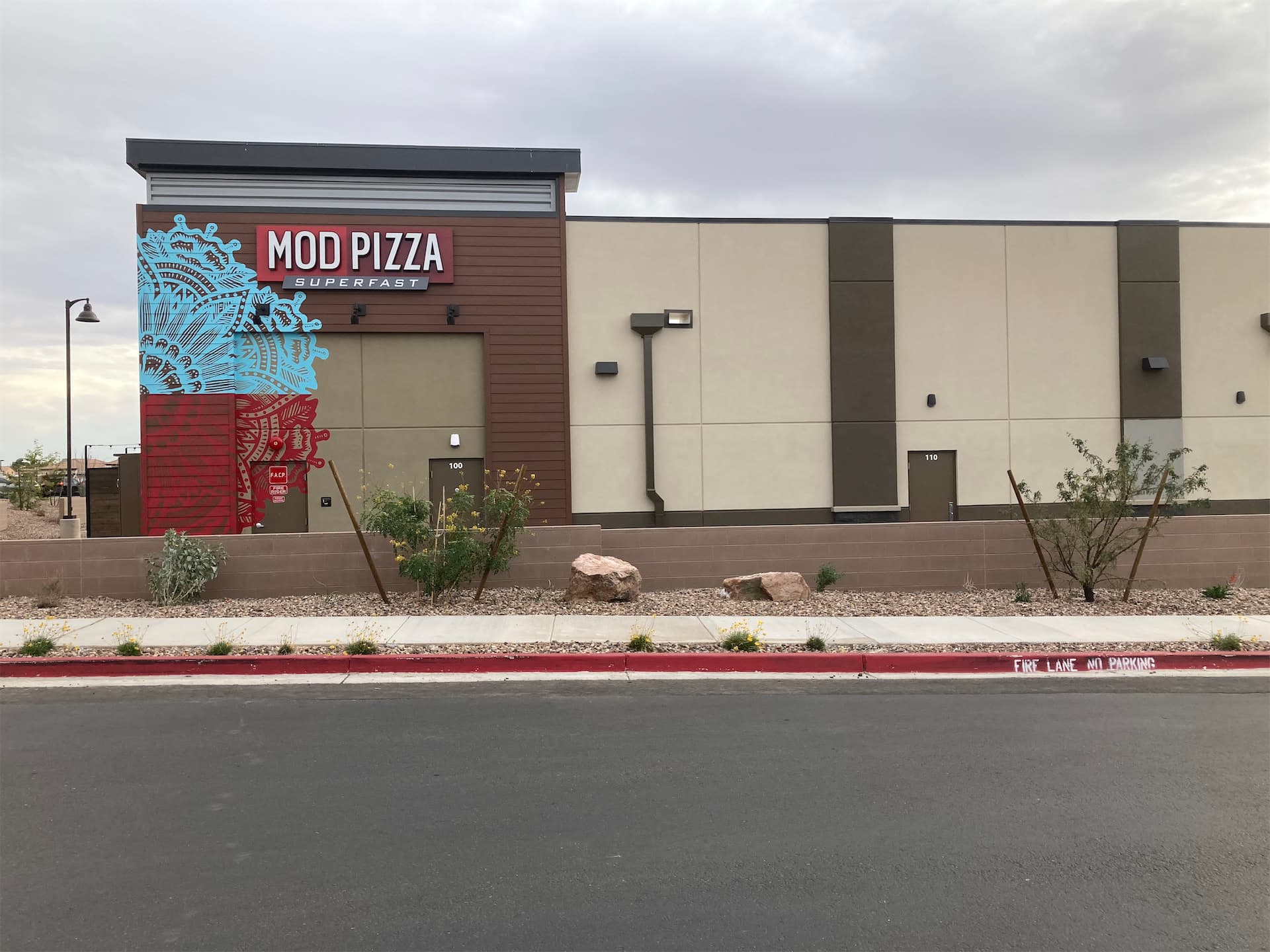 Exterior of a MOD Pizza restaurant featuring custom wall graphics and an illuminated store sign.