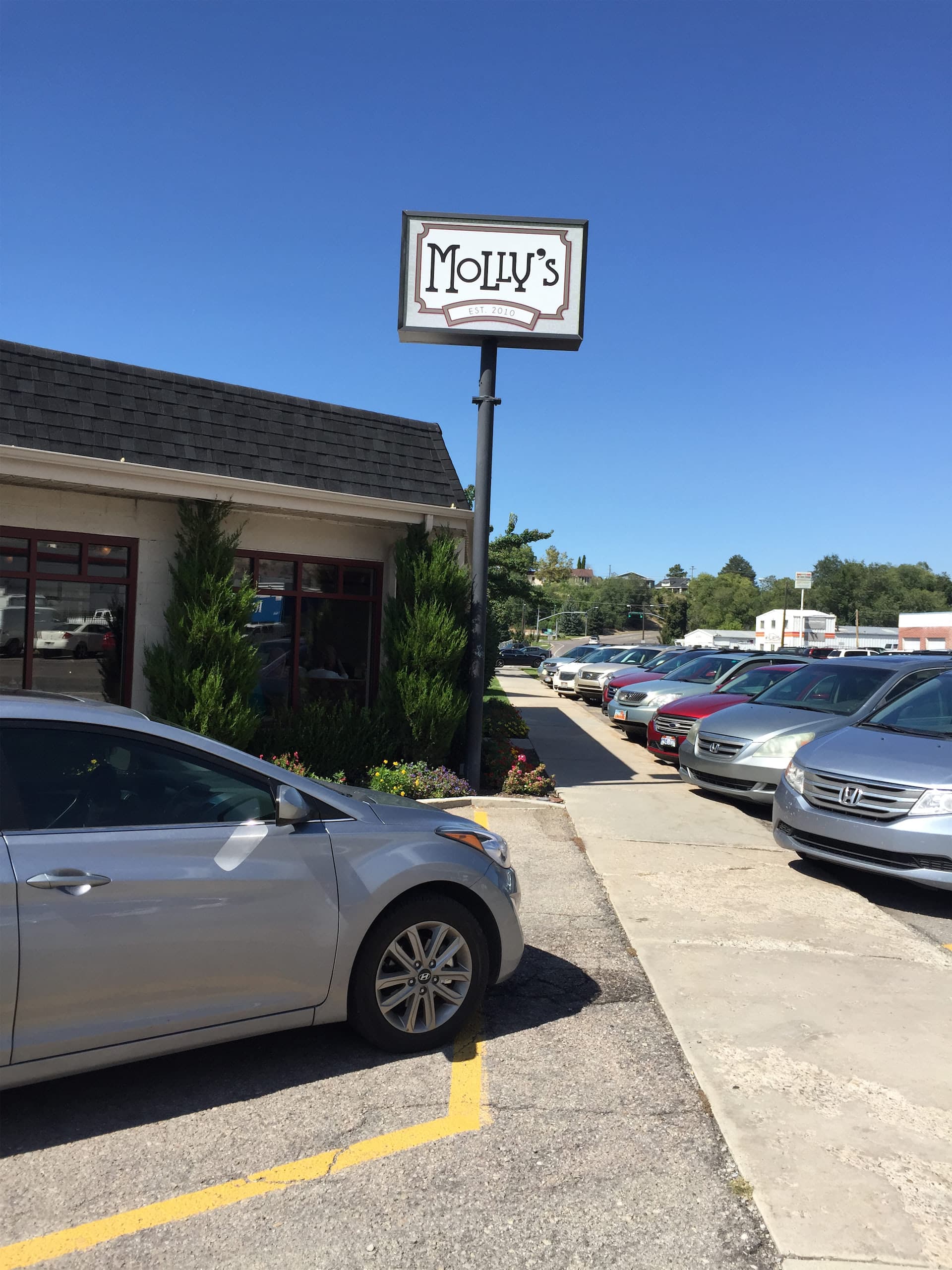 Outdoor pole sign for Molly's restaurant with a parking lot in the background.