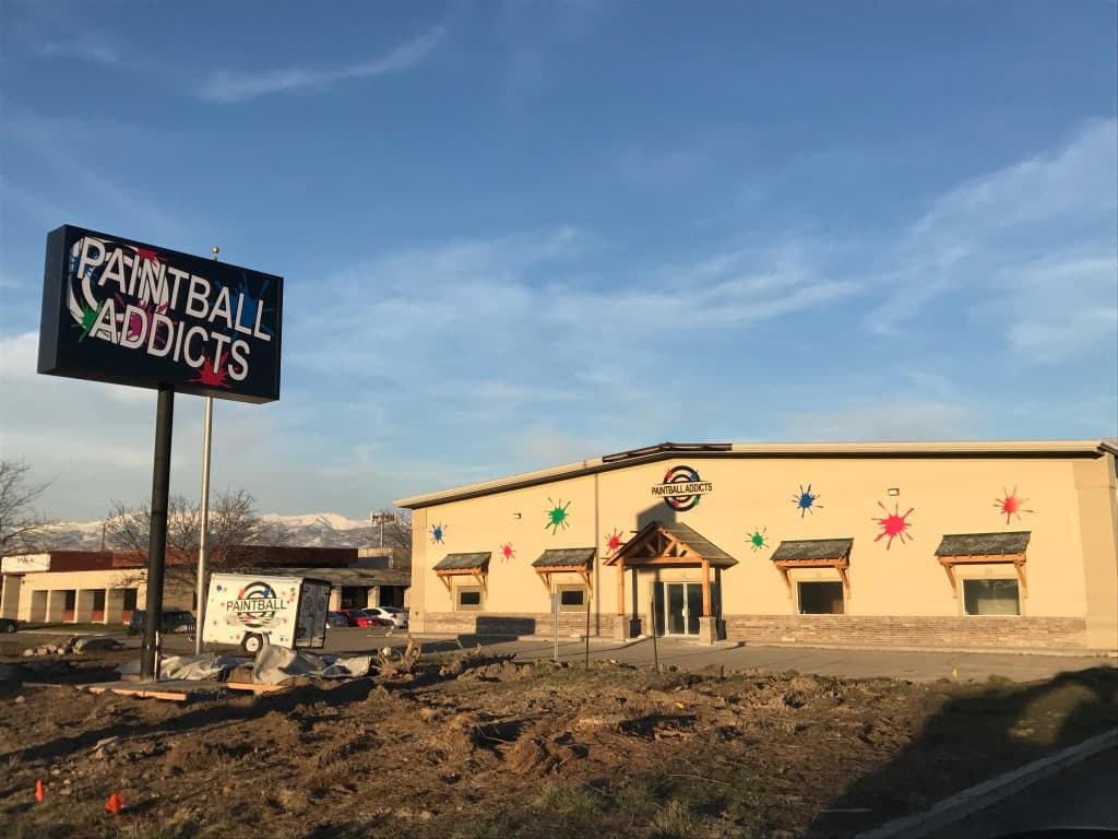 Paintball Addicts building with a large illuminated pylon sign and paint splatter wall decals.