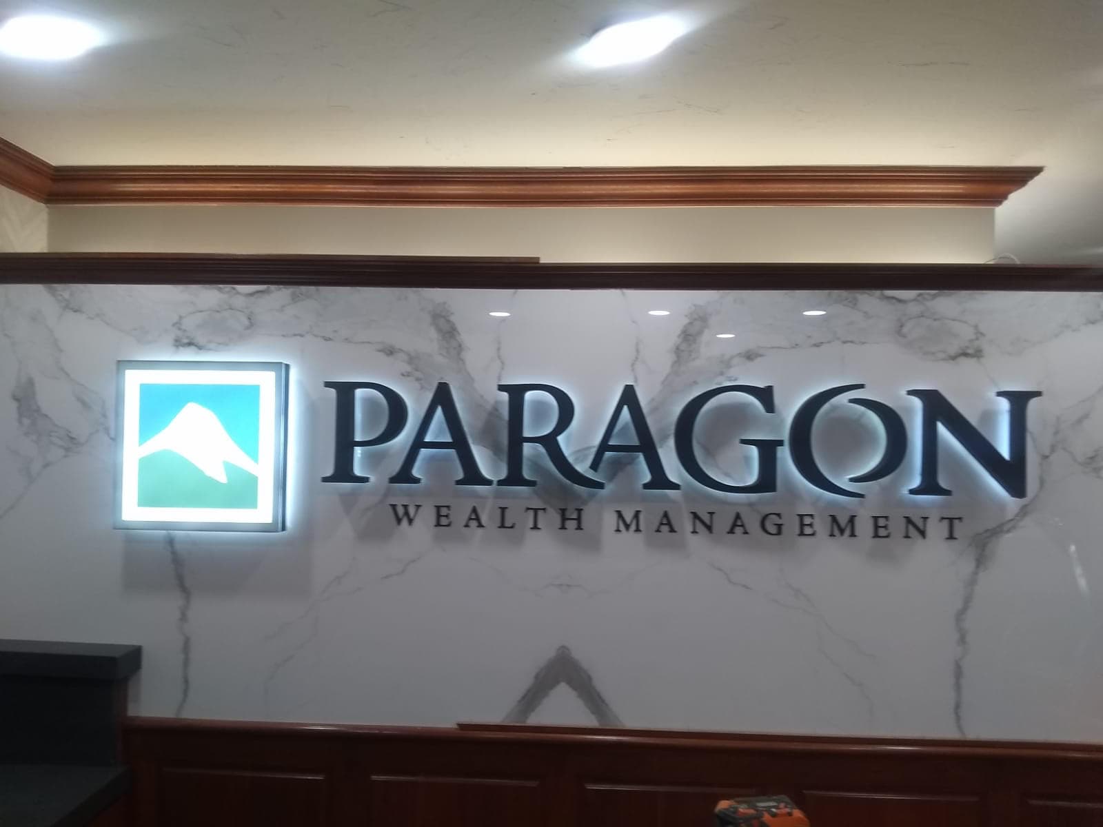 Illuminated Paragon Wealth Management lobby sign on a marble accent wall.