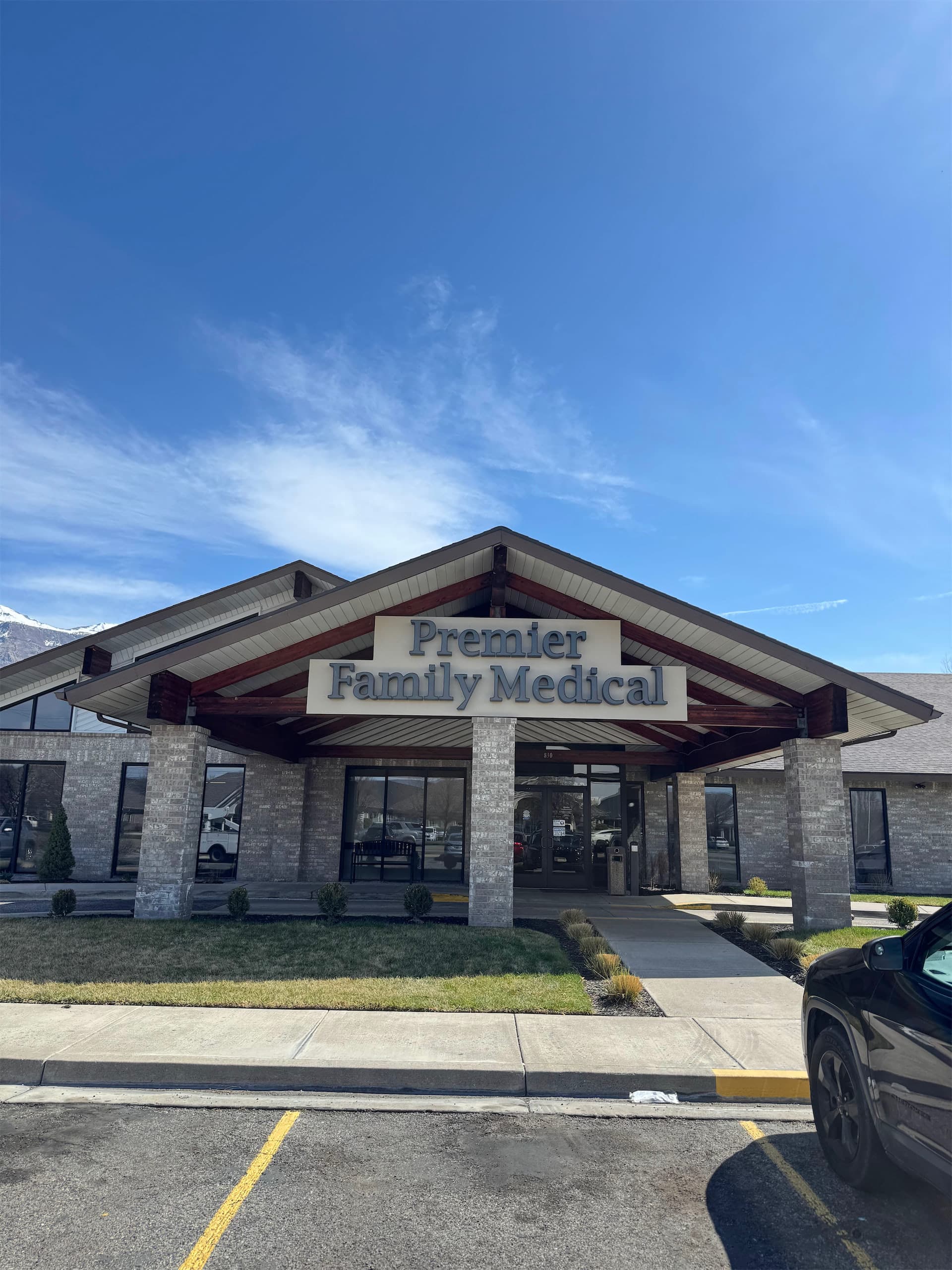 Exterior building sign reading Premier Family Medical mounted above a brick entrance under a clear blue sky.