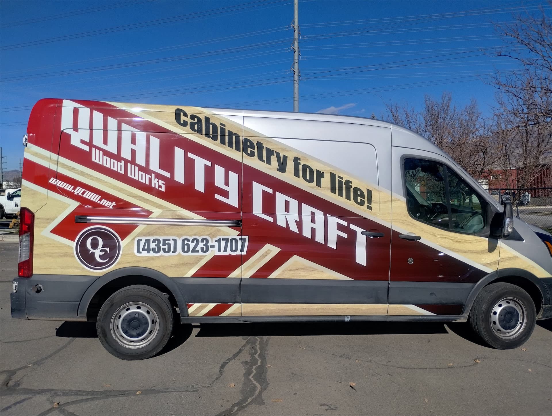 Silver commercial van featuring a burgundy and woodgrain custom vehicle wrap for Quality Craft Wood Works.