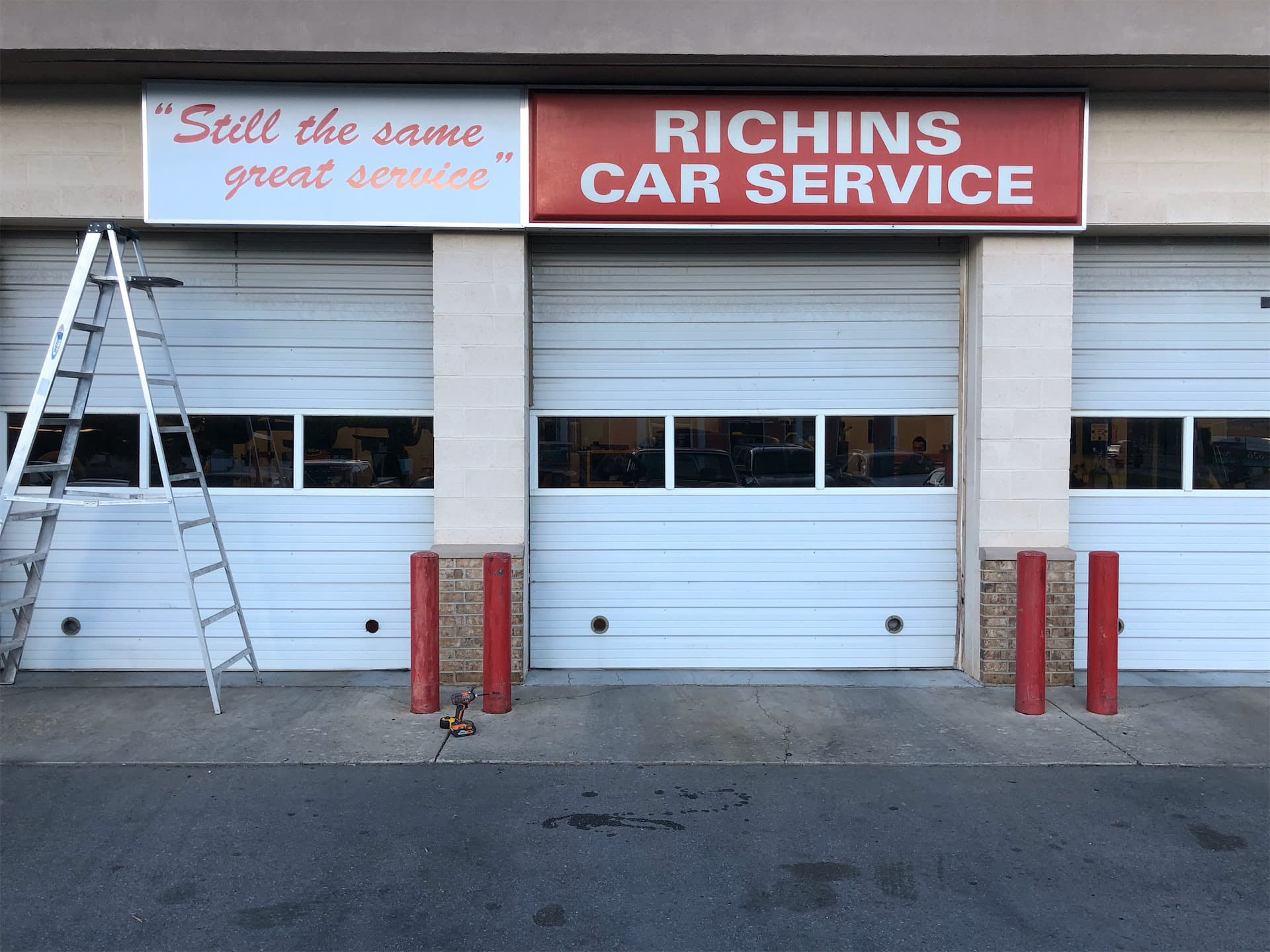 Red and white exterior building sign for Richins Car Service mounted above auto repair bay doors.