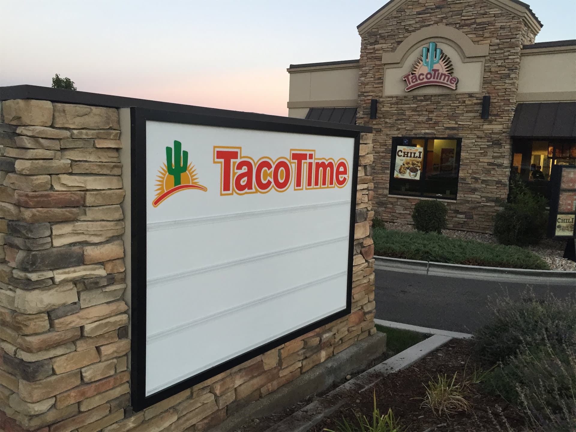Taco Time outdoor monument sign set in stone brickwork in front of the restaurant building.