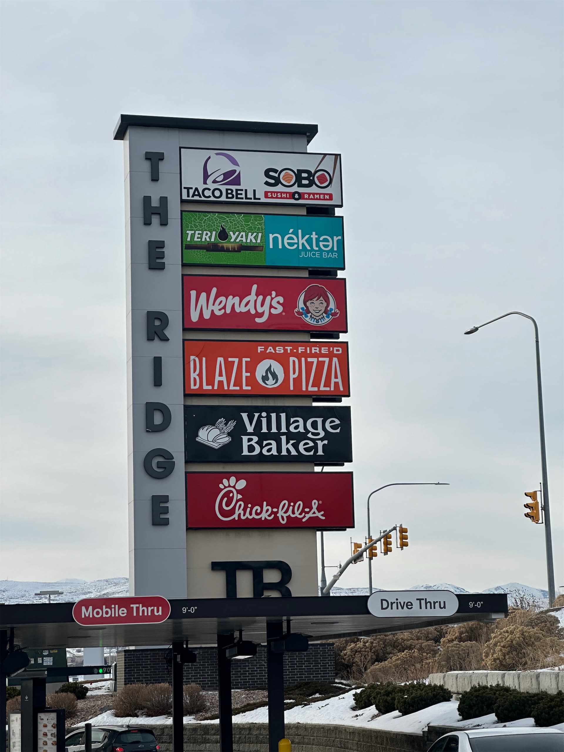 Large pylon sign for The Ridge featuring tenant logos including Wendy's, Blaze Pizza, and Chick-fil-A above drive-thru lanes.
