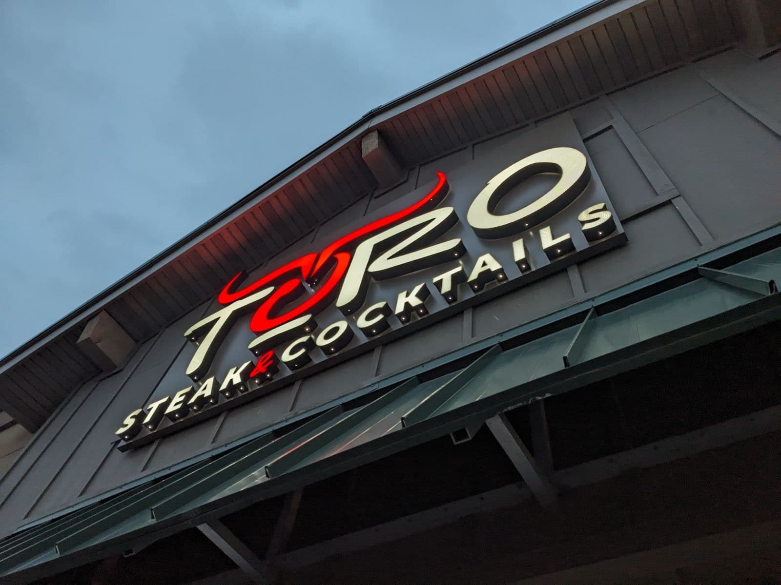 Illuminated exterior sign for Toro Steak and Cocktails mounted on a building facade.