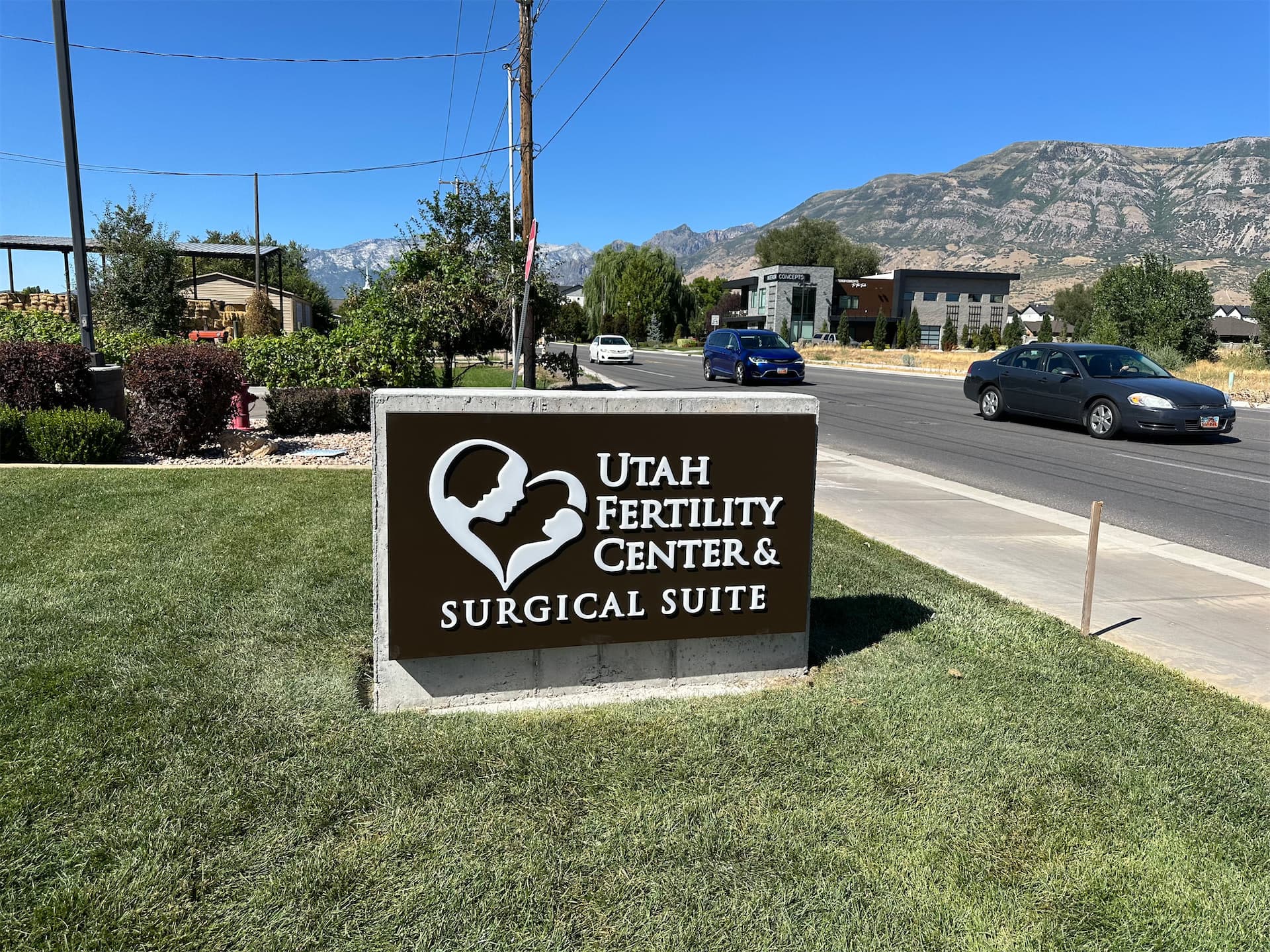 Utah Fertility Center & Surgical Suite monument sign on a grassy lawn near a road.