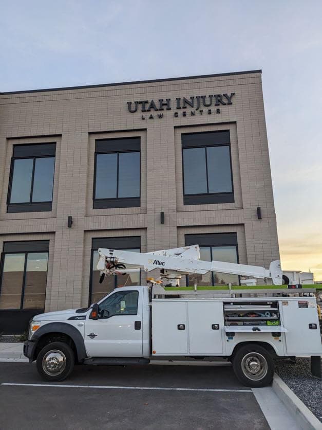 Service truck parked in front of Utah Injury Law Center building during exterior sign installation.
