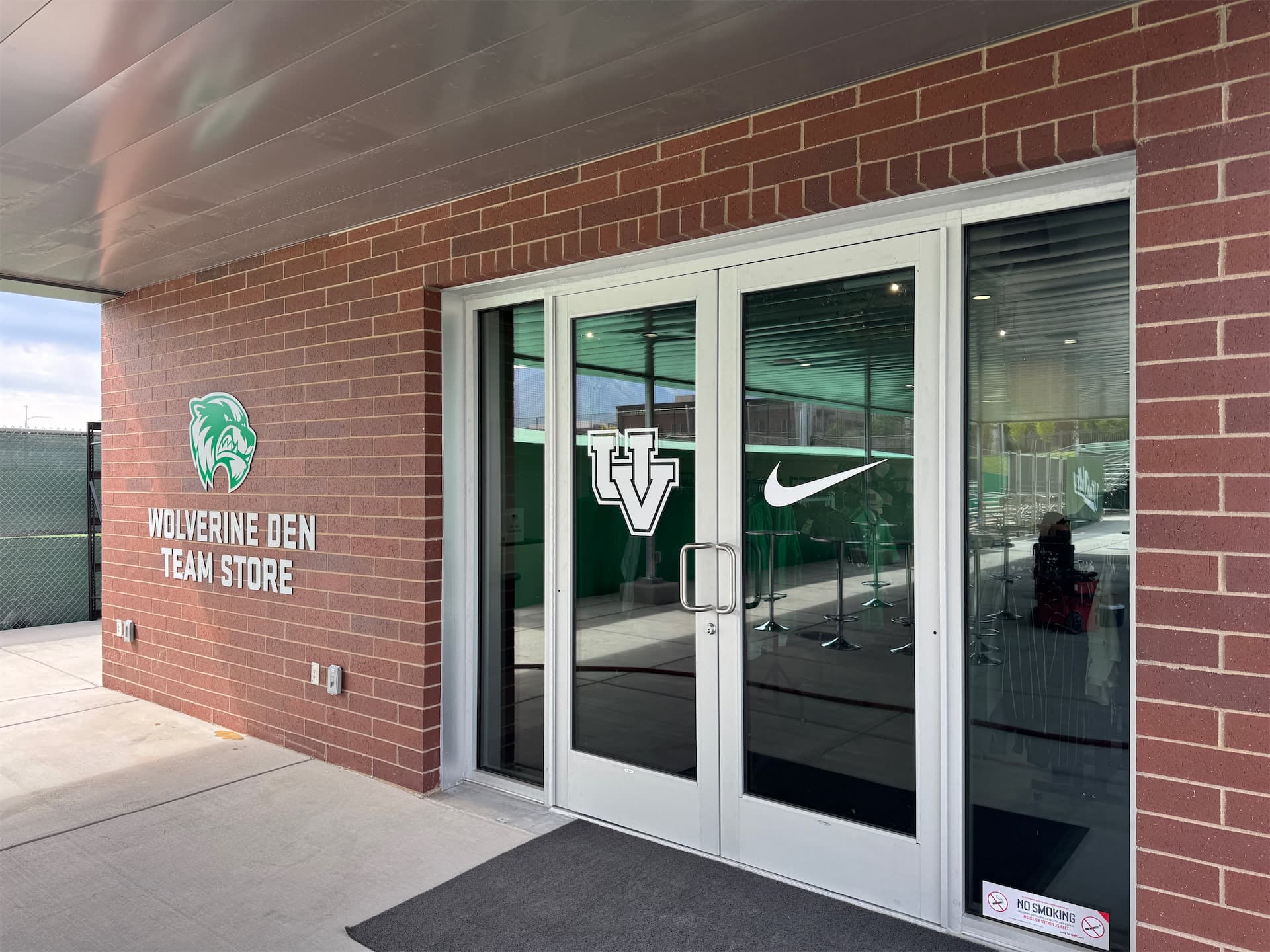 Exterior entrance to the Utah Valley University Wolverine Den Team Store with custom wall signage and door decals.