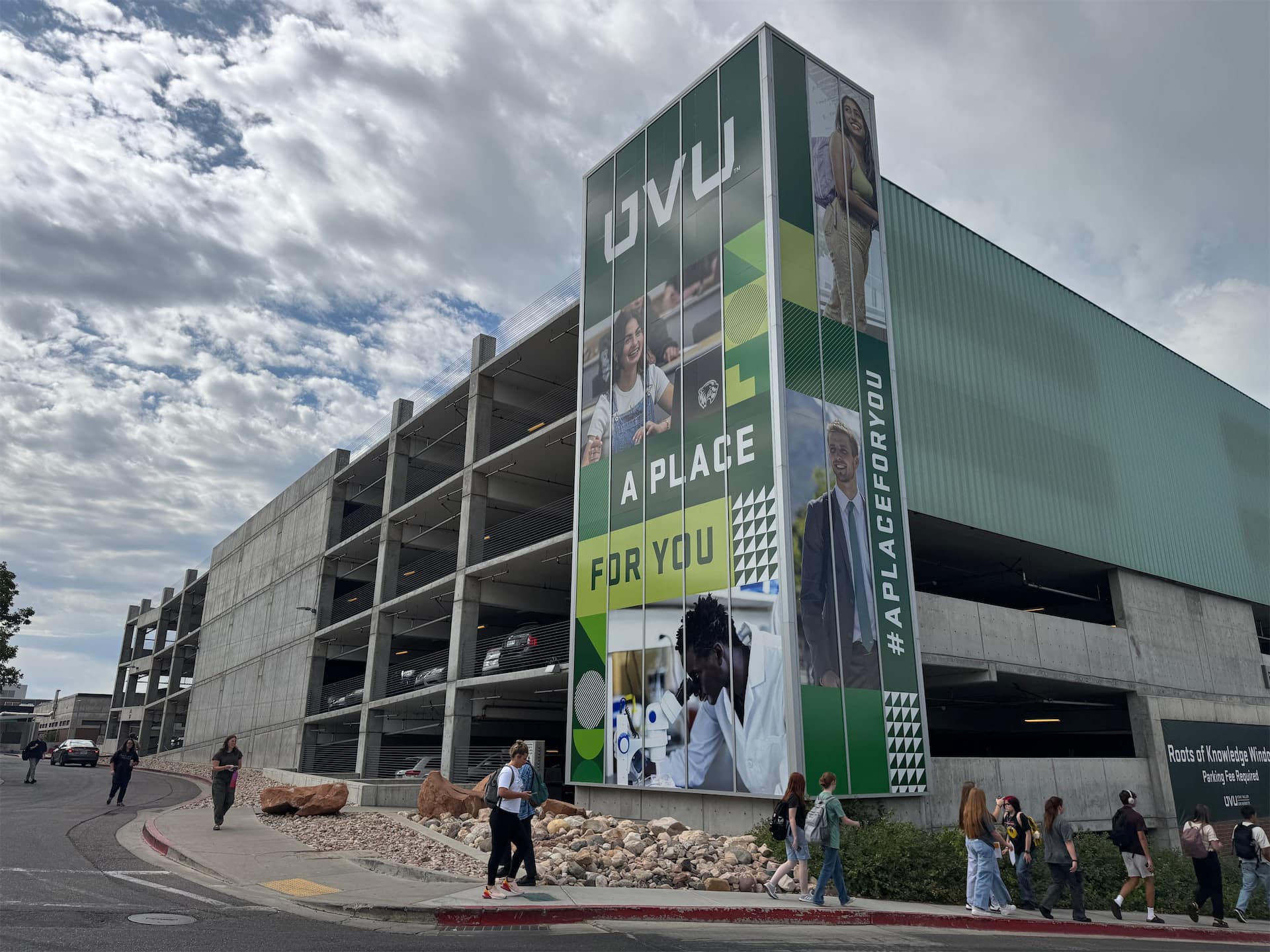 Large green graphic wall wrap featuring Utah Valley University branding on a multi-story parking garage.