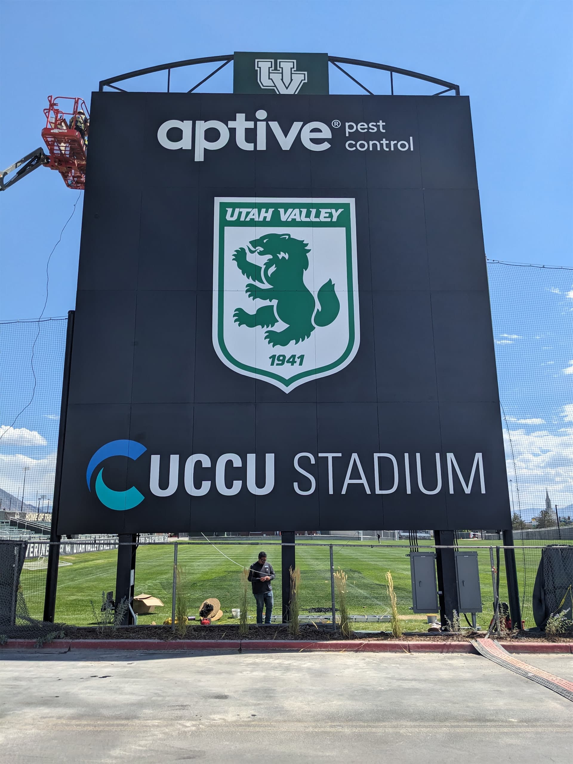 Large black UCCU Stadium sign featuring the Utah Valley wolverine emblem and Aptive logo.