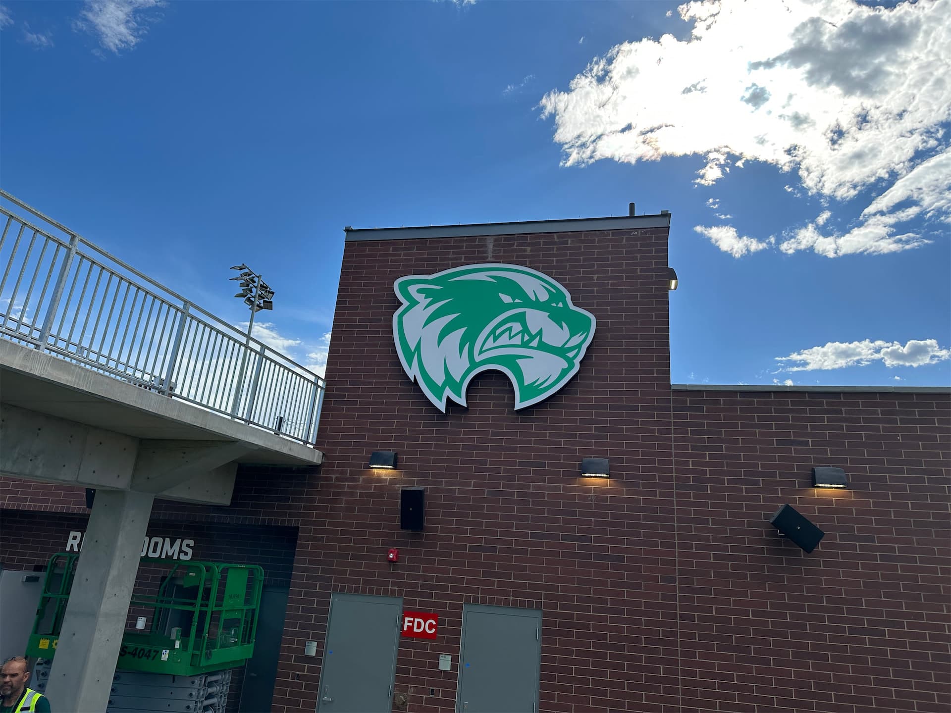 Green and white Utah Valley University wolverine logo installed on a brick stadium wall.