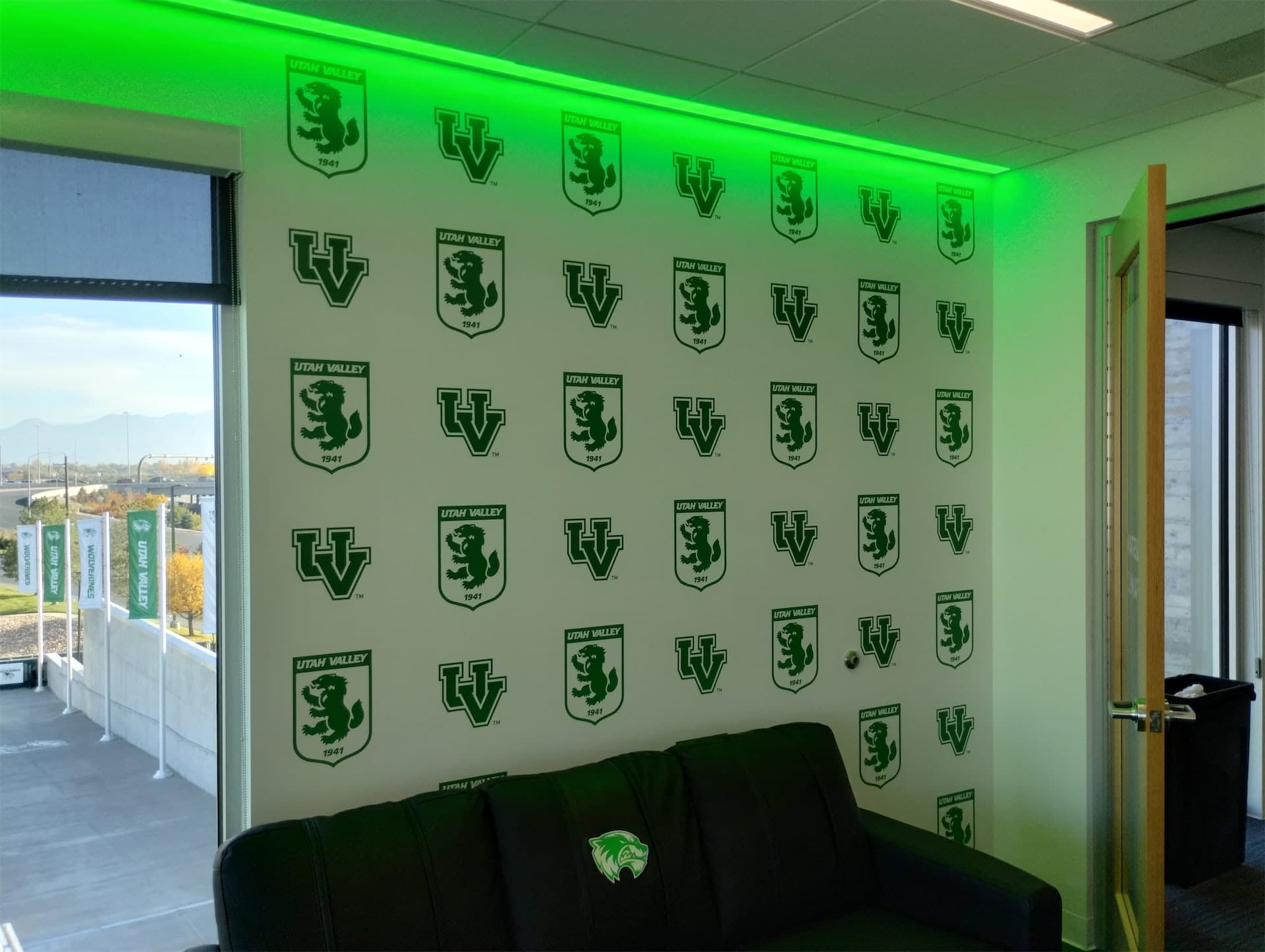 Utah Valley University branded step-and-repeat wall graphic with green LED lighting.