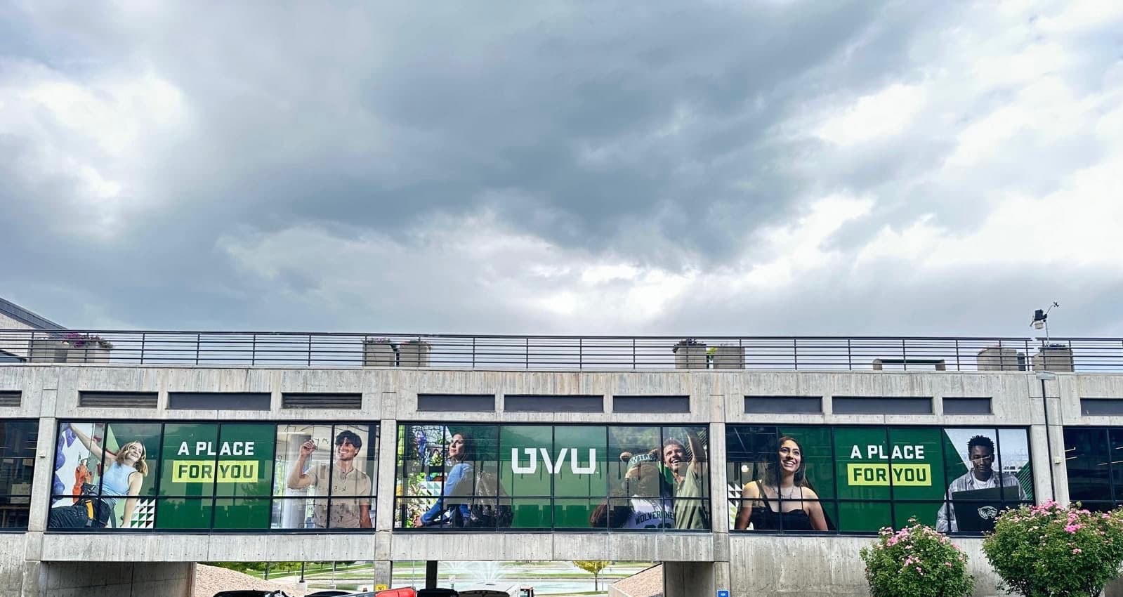 Large exterior window graphics on a Utah Valley University pedestrian bridge with student images and UVU branding.